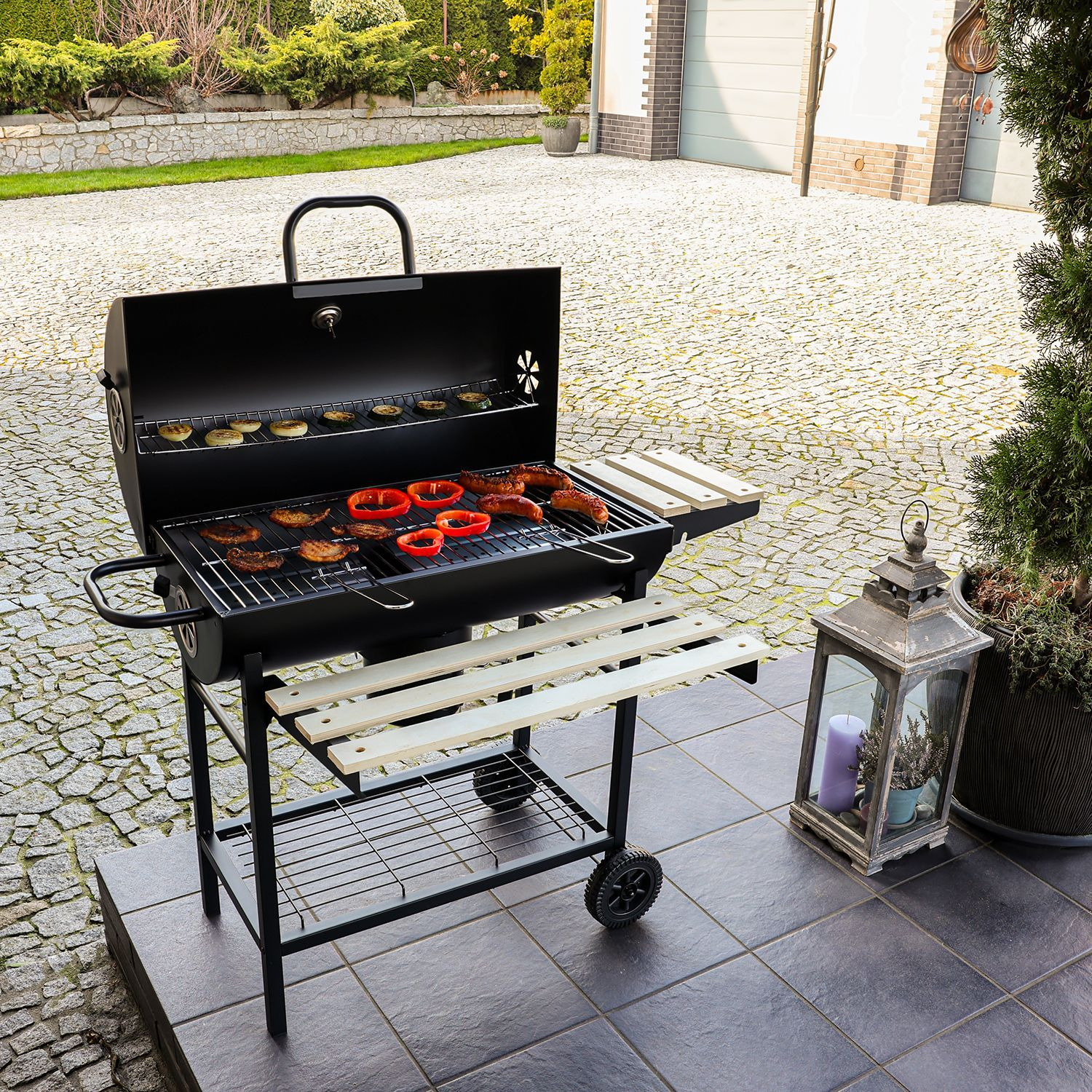 Czarny grill z mięsem i papryką, obok lampion ze świecą.