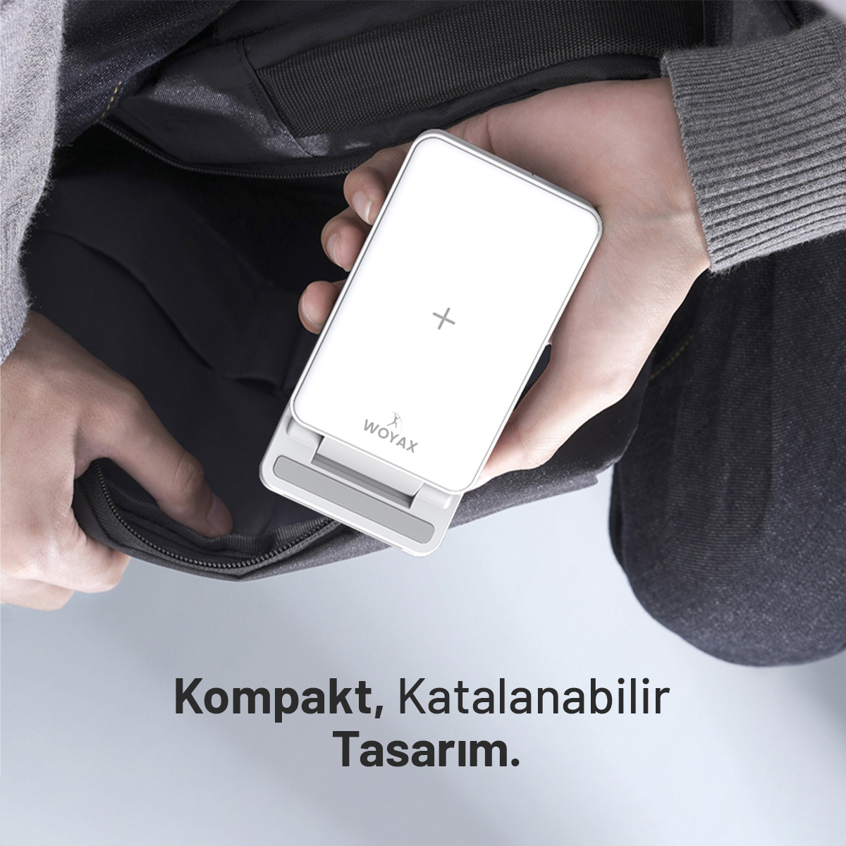 Bir el, Woyax logolu beyaz, katlanabilir şarj cihazı tutuyor.