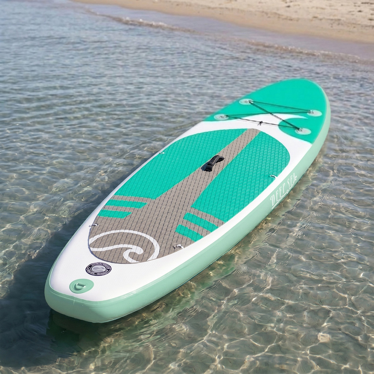 Zielona i biała deska paddleboard unosi się na czystej wodzie blisko piaszczystej plaży.