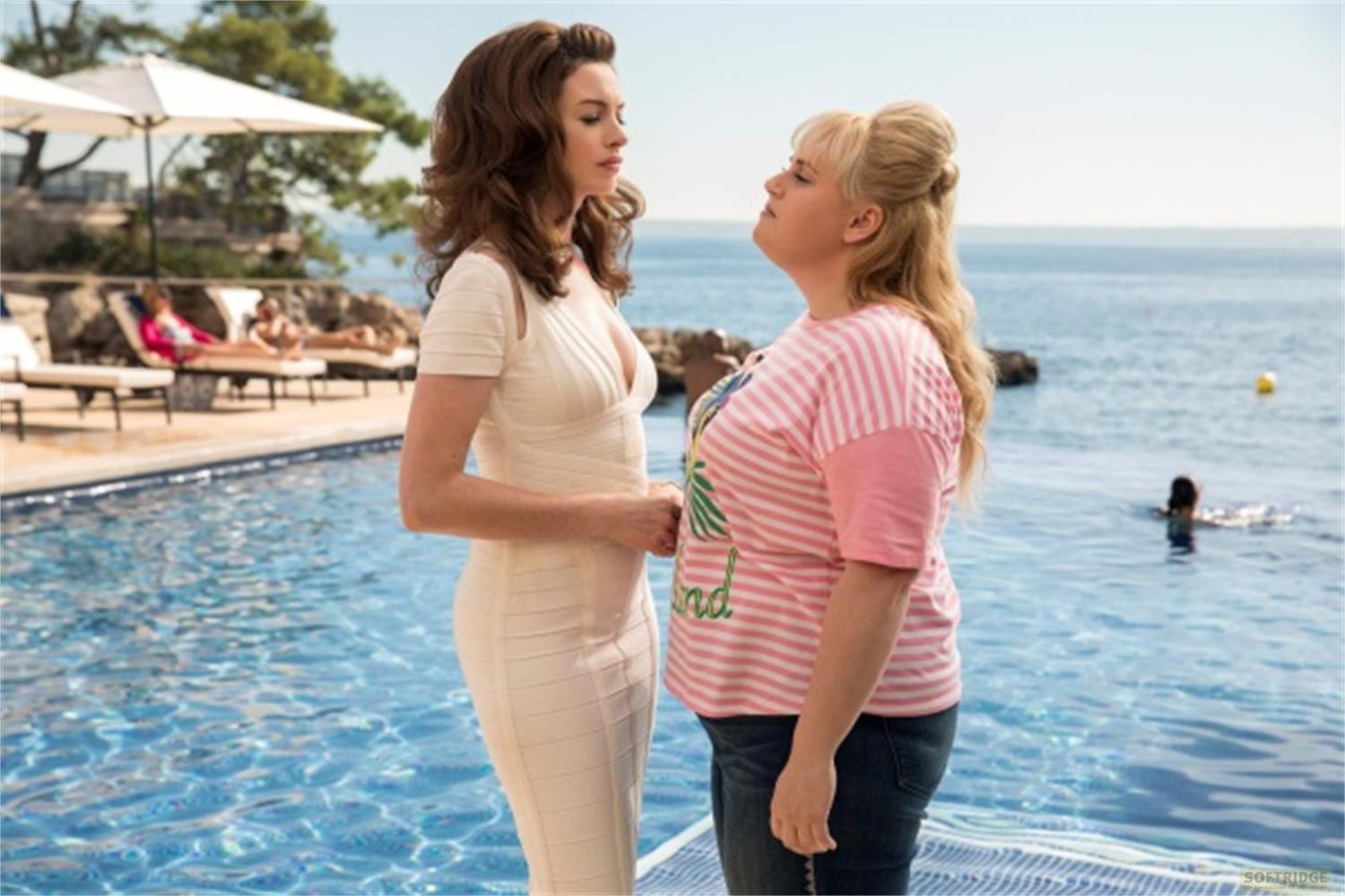 Zwei Frauen stehen am Pool. Im Hintergrund liegen Liegen und das Meer.