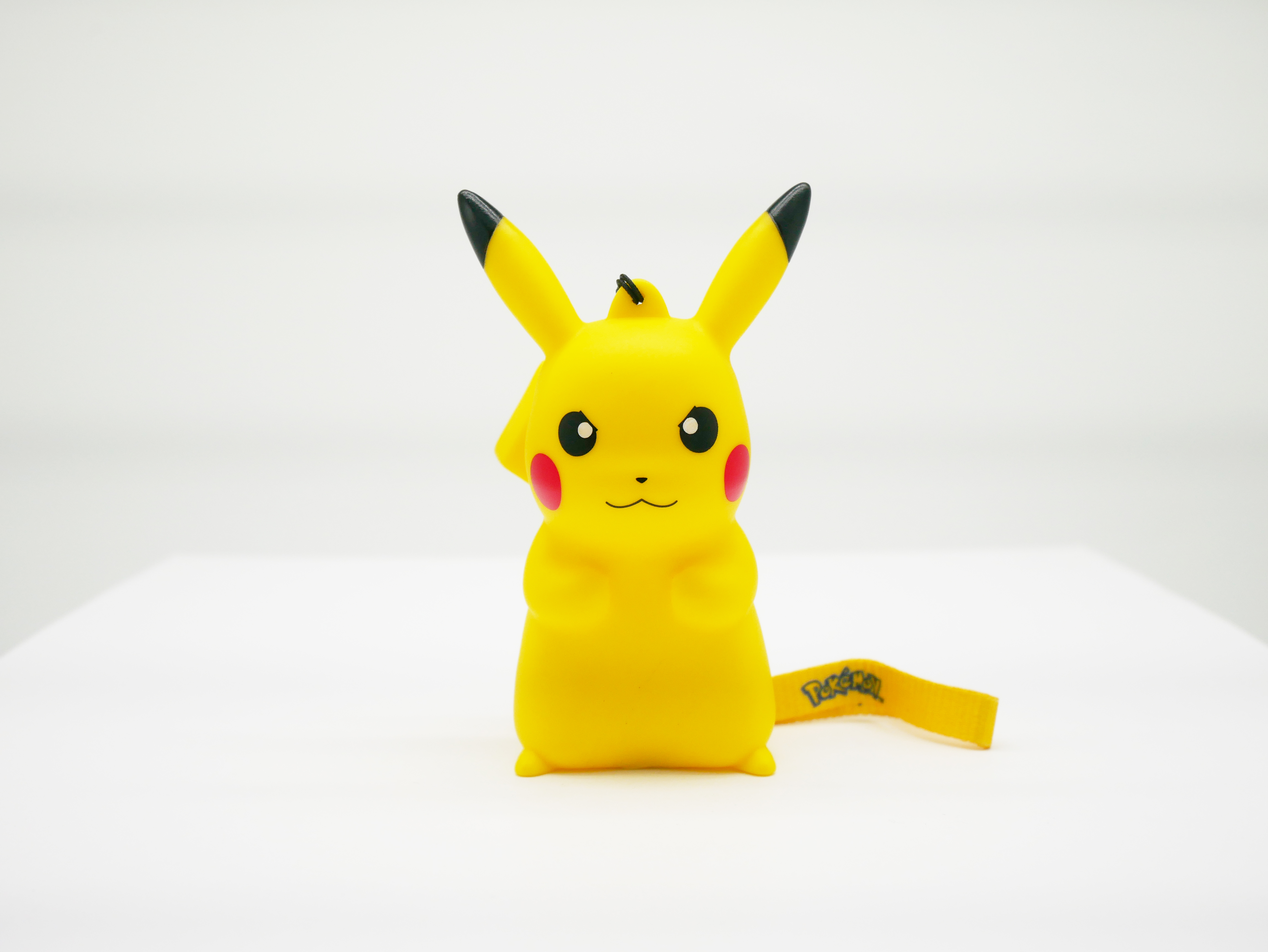 Gelbe Pikachu-Figur mit schwarzen Ohrspitzen und roten Wangen auf weißem Hintergrund.