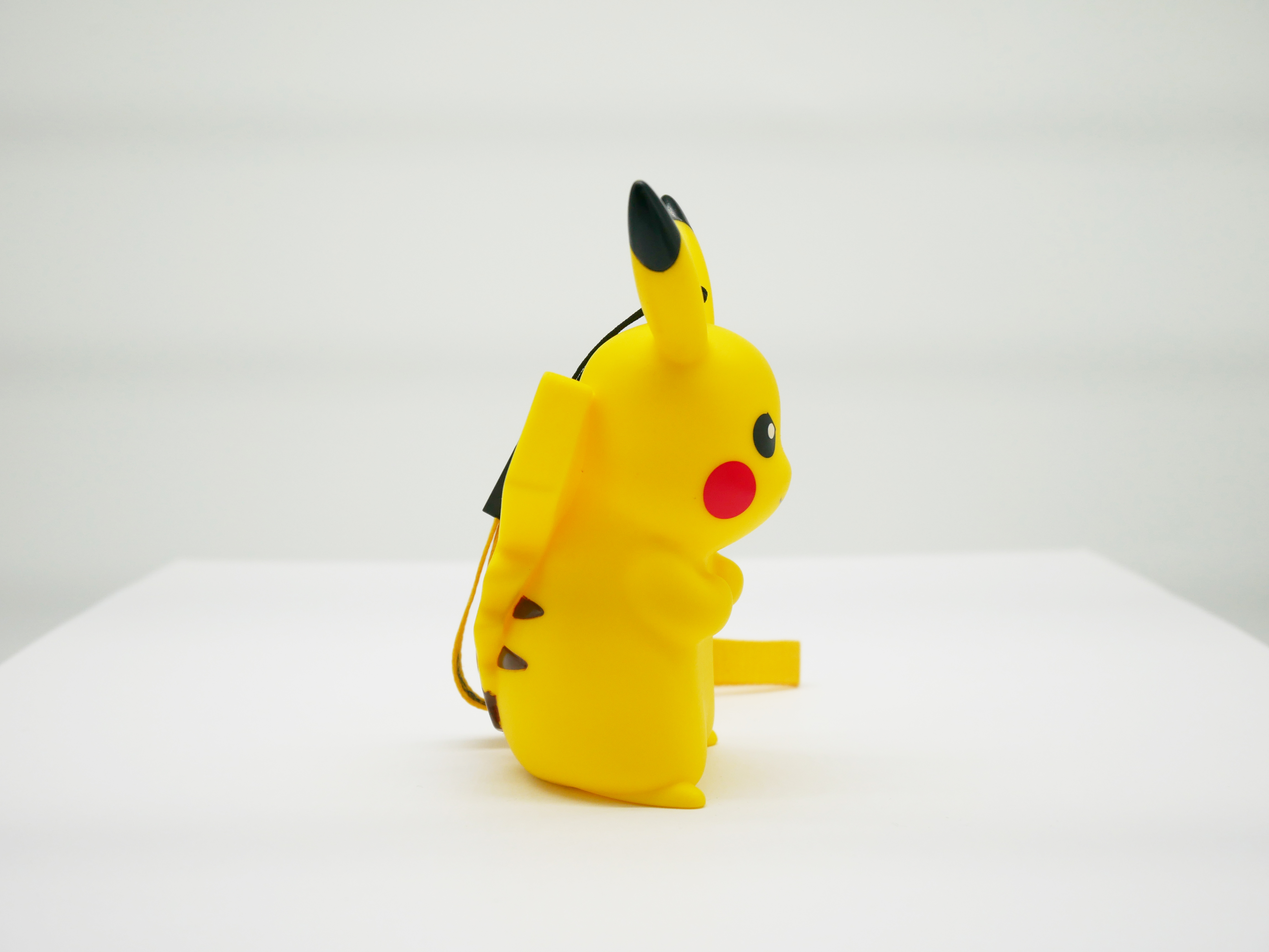 Gelbe Pikachu-Figur mit schwarzen Ohren und roten Wangen auf weißem Hintergrund.