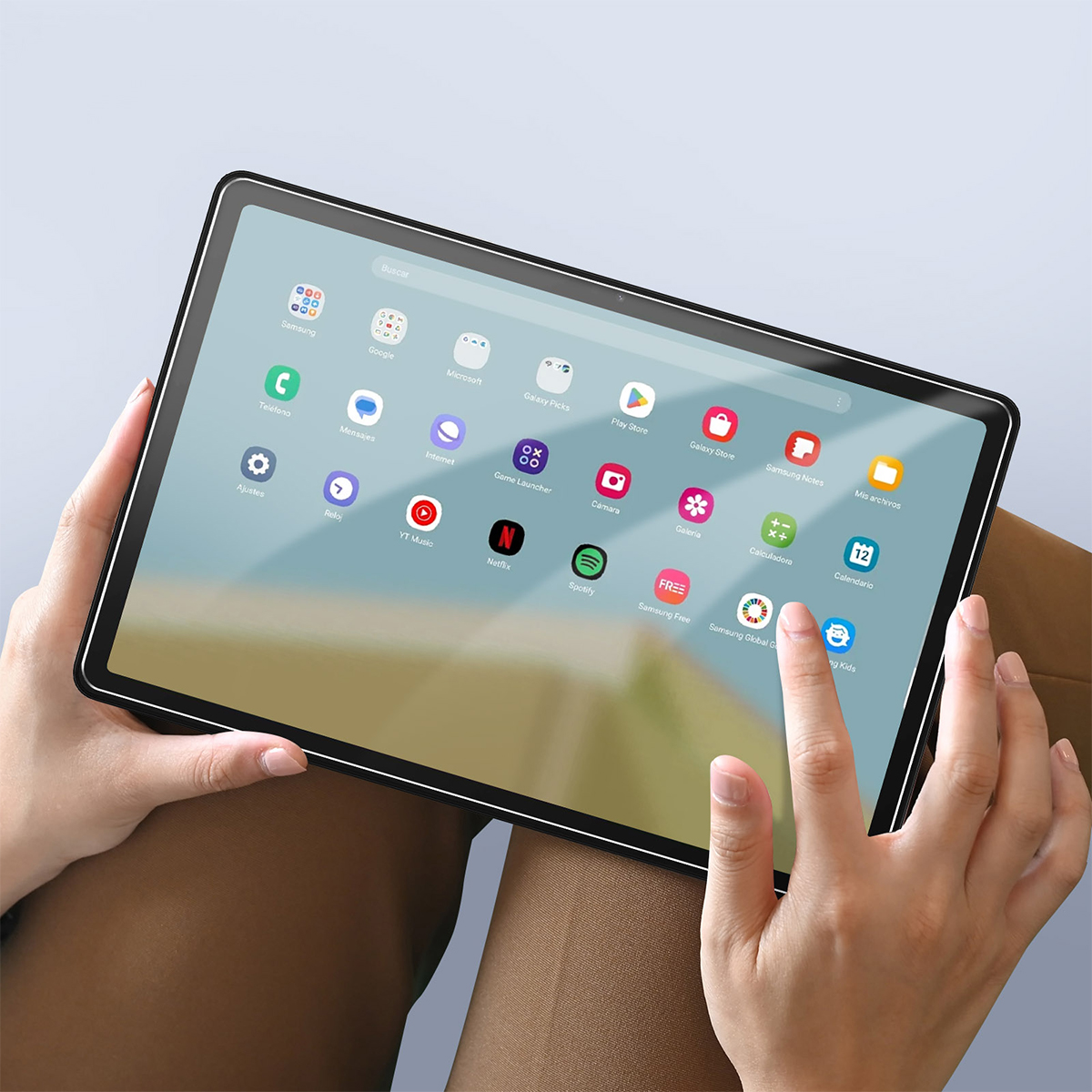 Une personne tient une tablette affichant une grille d'applications à l'écran.