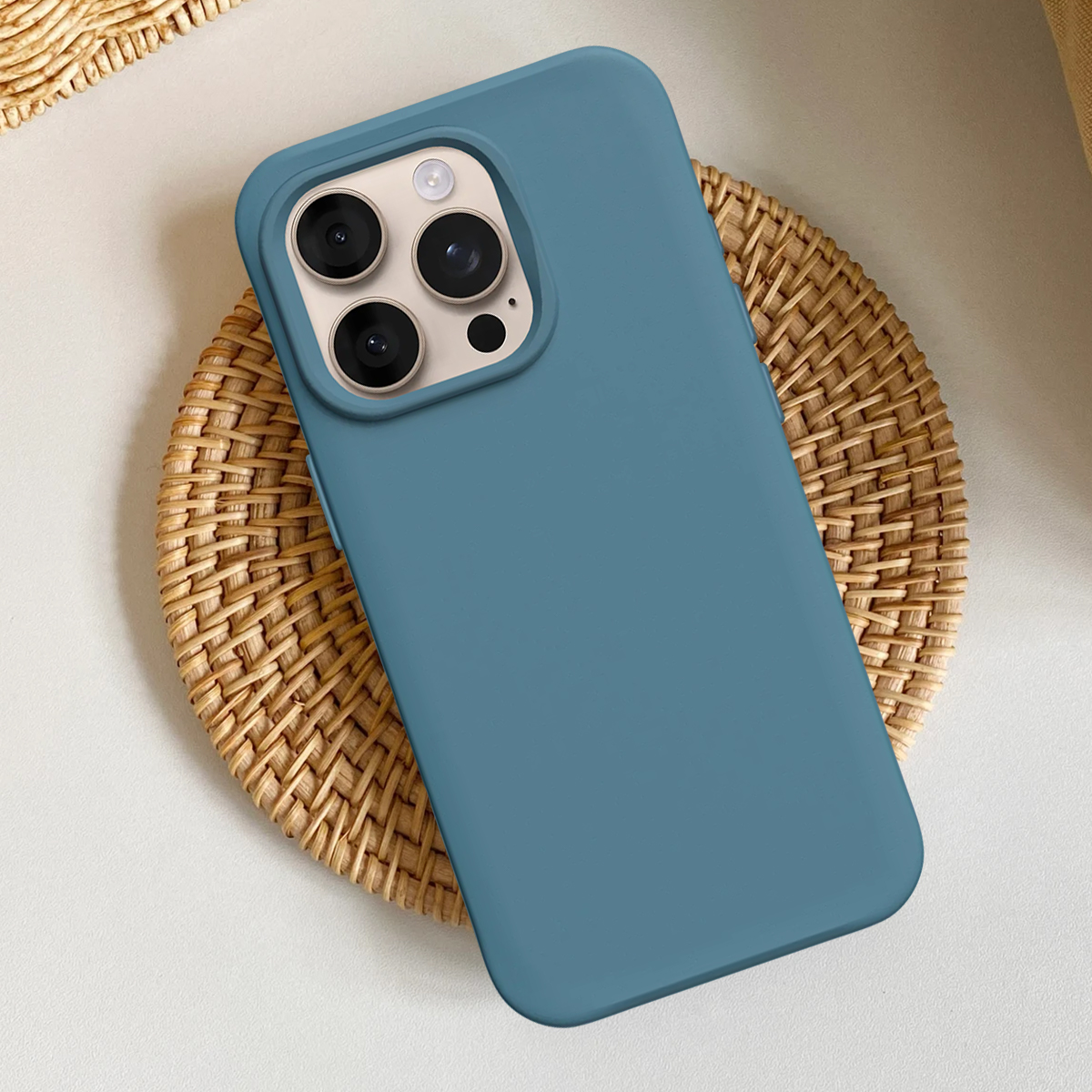 Een blauwe telefoonhoes met drie camera's ligt op een geweven mat.