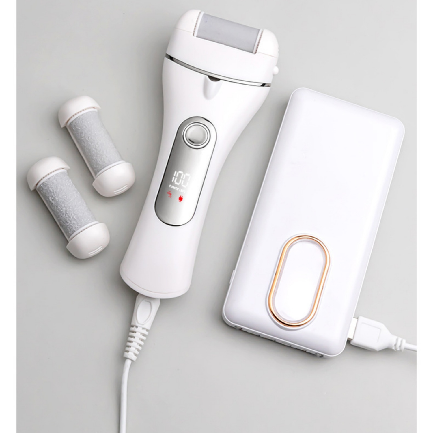 Ein weißer elektrischer Hornhautentferner mit Ersatzaufsätzen und Powerbank.