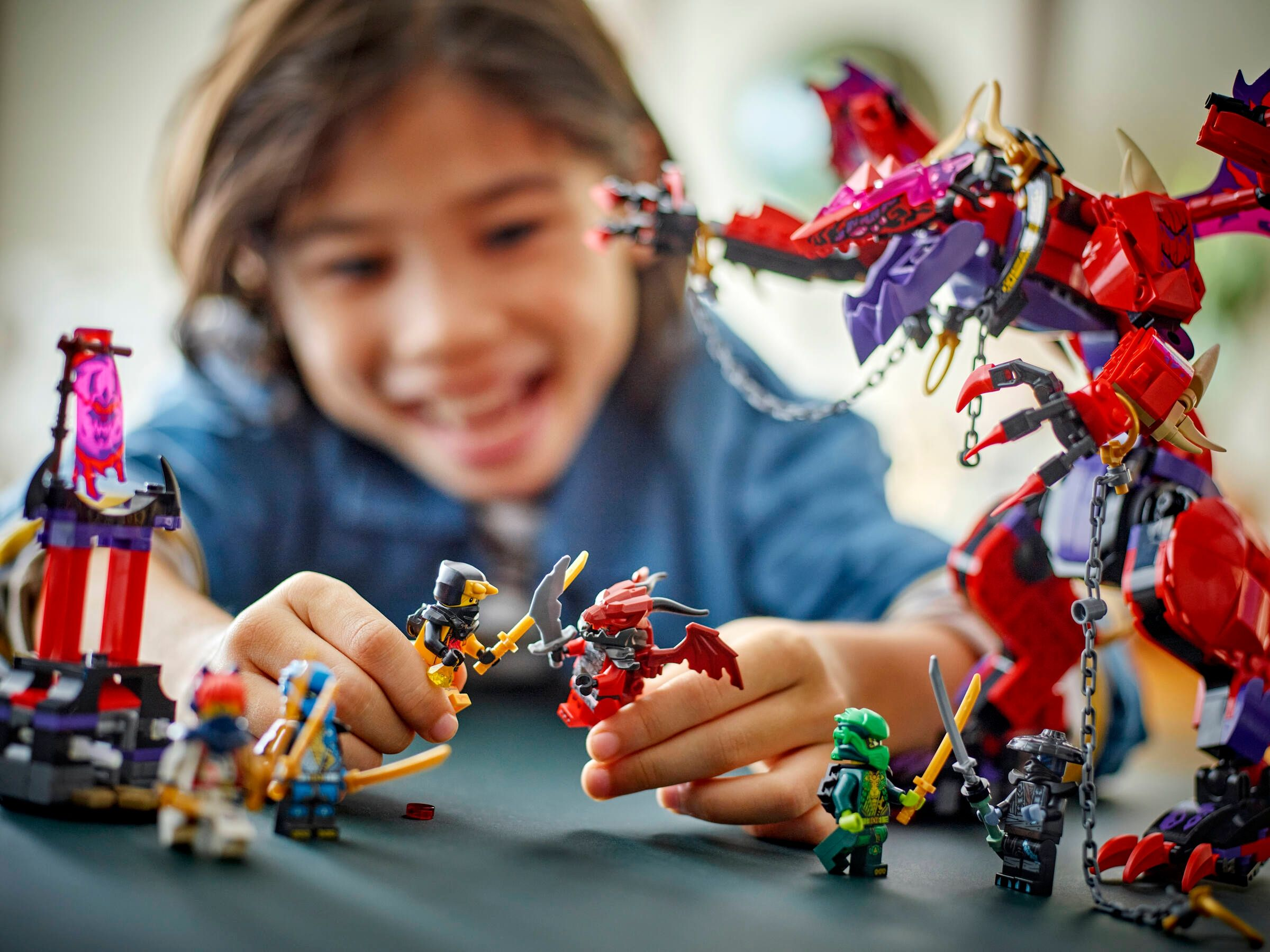 Ein Kind spielt mit Lego-Figuren und einem roten Lego-Drachen.