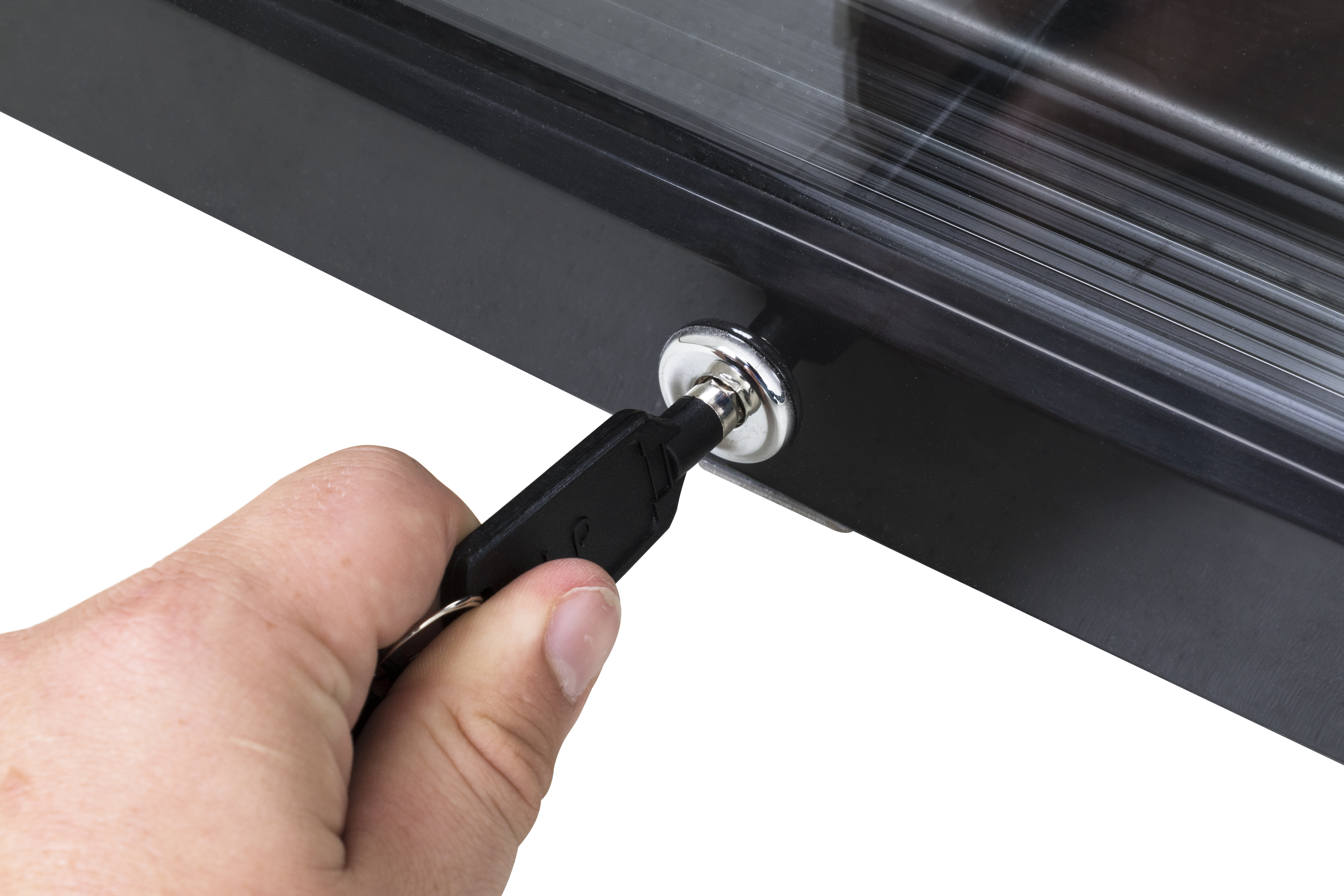 A hand inserts a black key with a silver ring into a lock.