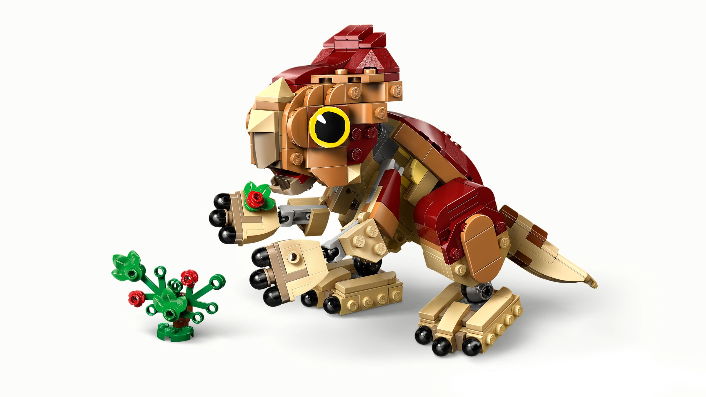 Ein Lego-Dinosaurier mit gelbem Auge und rotem Blatt frisst eine kleine grüne Pflanze mit roten Beeren.