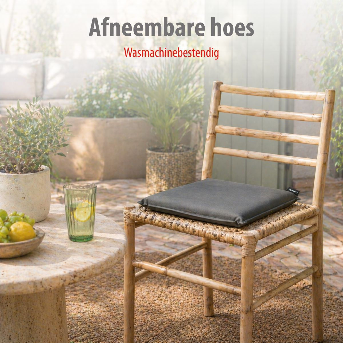 A wooden chair with a cushion sits on a gravel path next to a table with fruit and drinks.