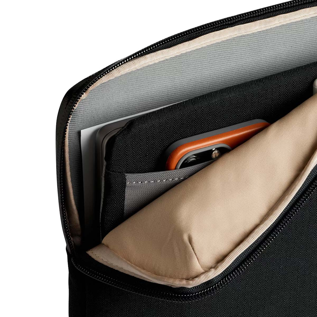 Un telefono arancione giace in una borsa nera con fodera beige.