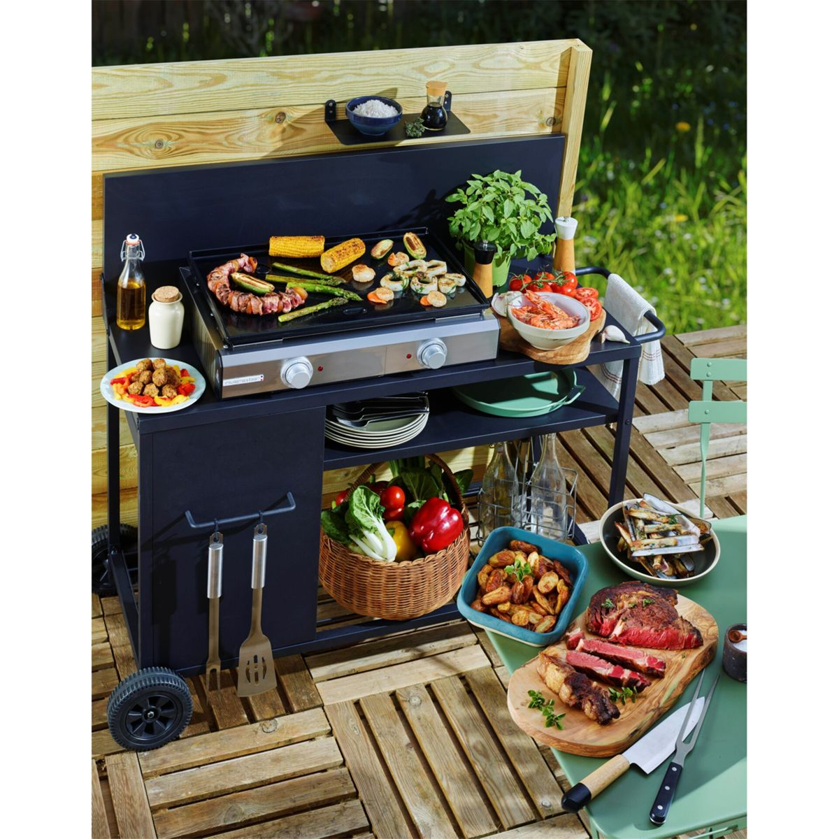 Eine schwarze Outdoor-Grillstation mit verschiedenen Speisen, die auf einer Grillplatte zubereitet werden, darunter Mais, Spargel und Meeresfrüchte.