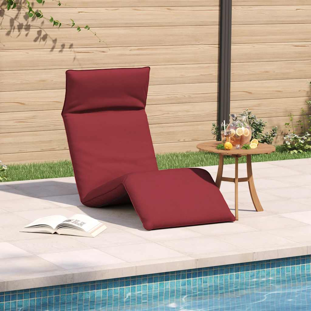 Rote Liege am Pool mit Buch und Getränk auf dem Beistelltisch.