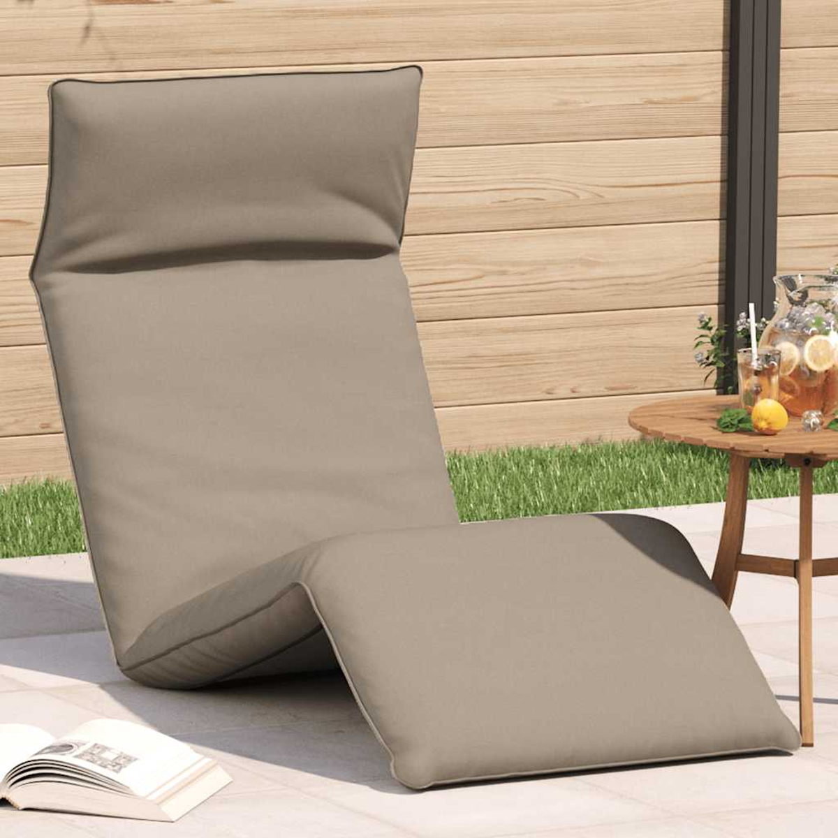 Ein beiger Liegestuhl steht auf einer Terrasse neben einem kleinen Tisch mit Getränken.