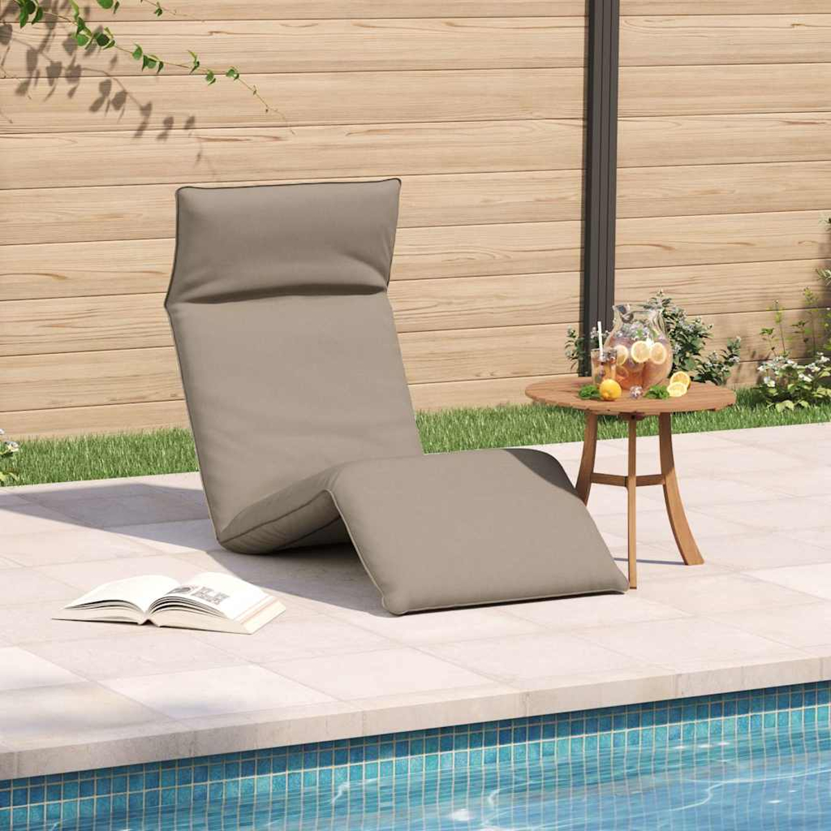 Grauer Liegestuhl am Pool mit Buch, Tisch mit Krug und Zitronen.