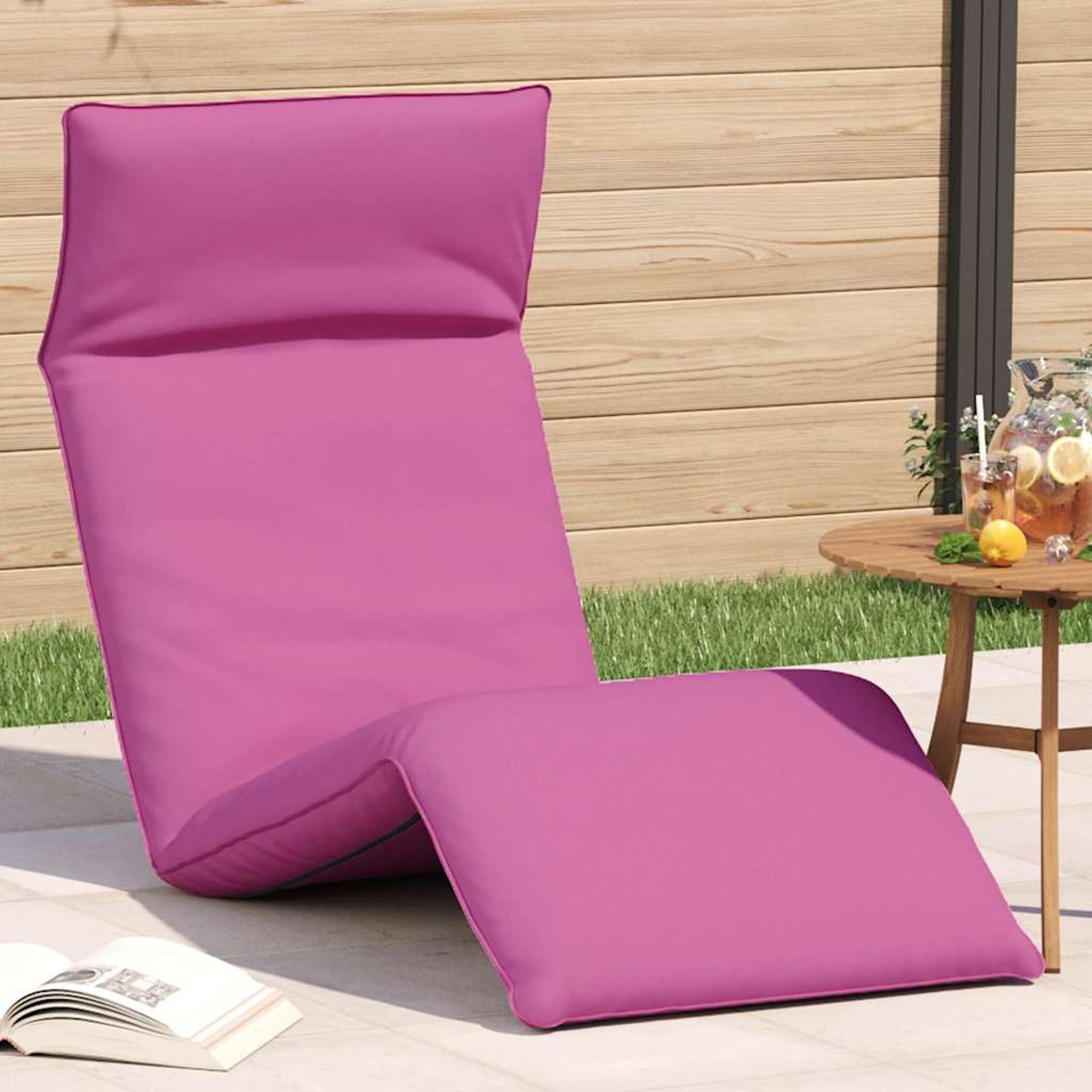 Ein pinker Liegestuhl steht auf einer Terrasse neben einem Holztisch mit Getränken.