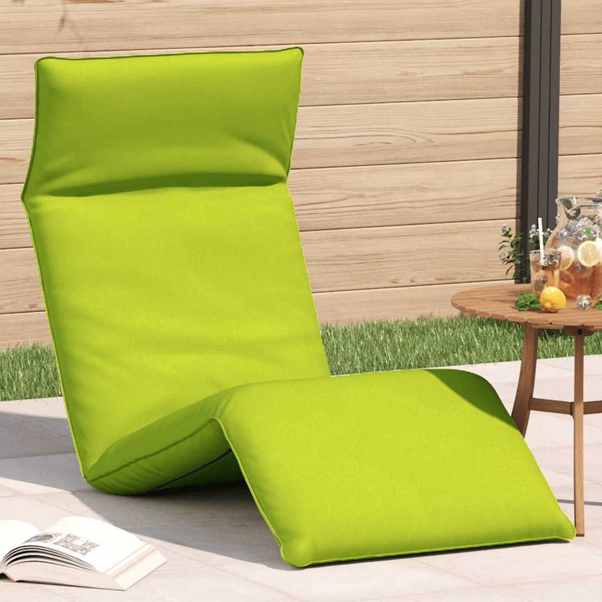 Una poltrona da lounge verde brillante all'aperto accanto a un tavolo con bevande.