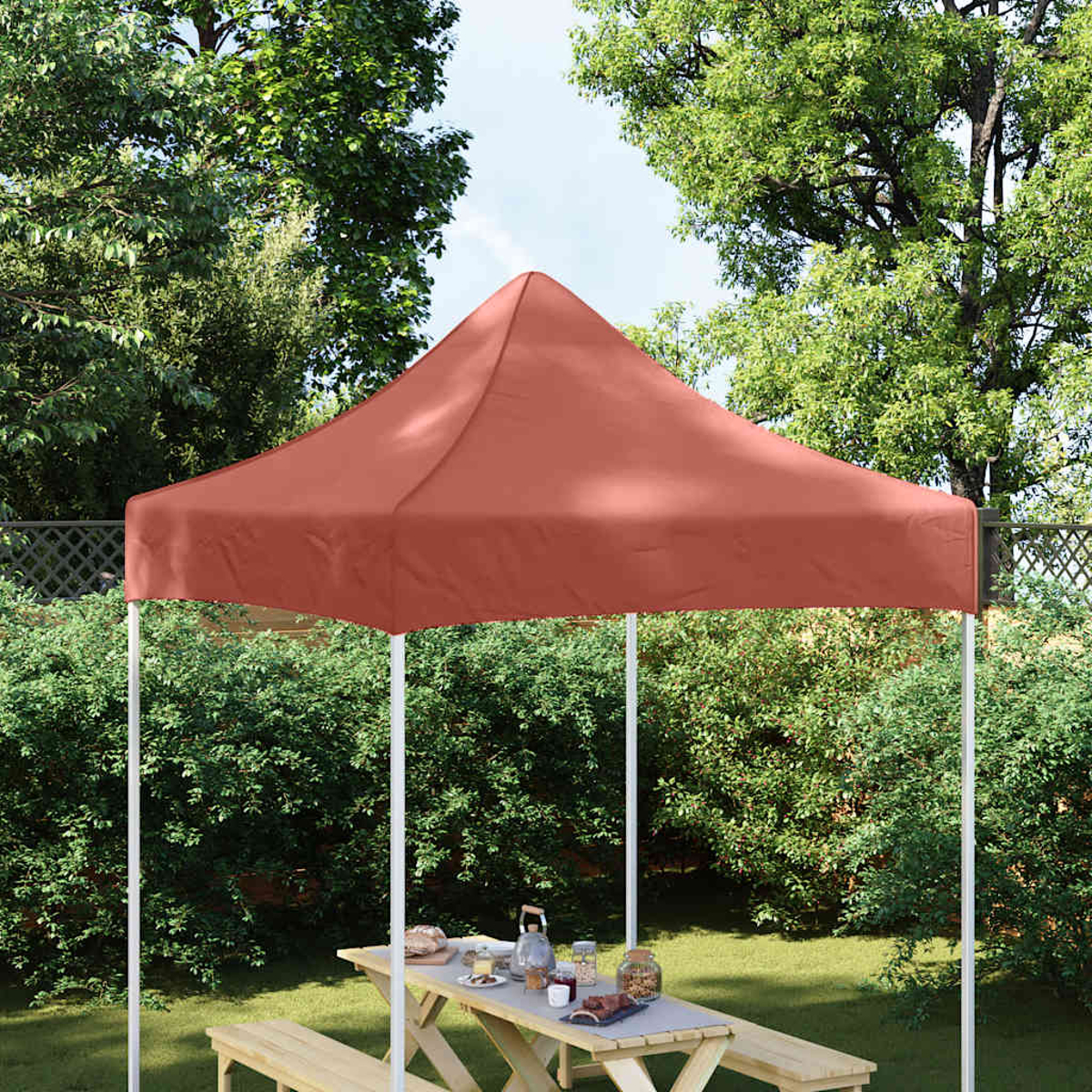 Una tettoia rossa copre un tavolo da picnic in legno con panche in giardino.
