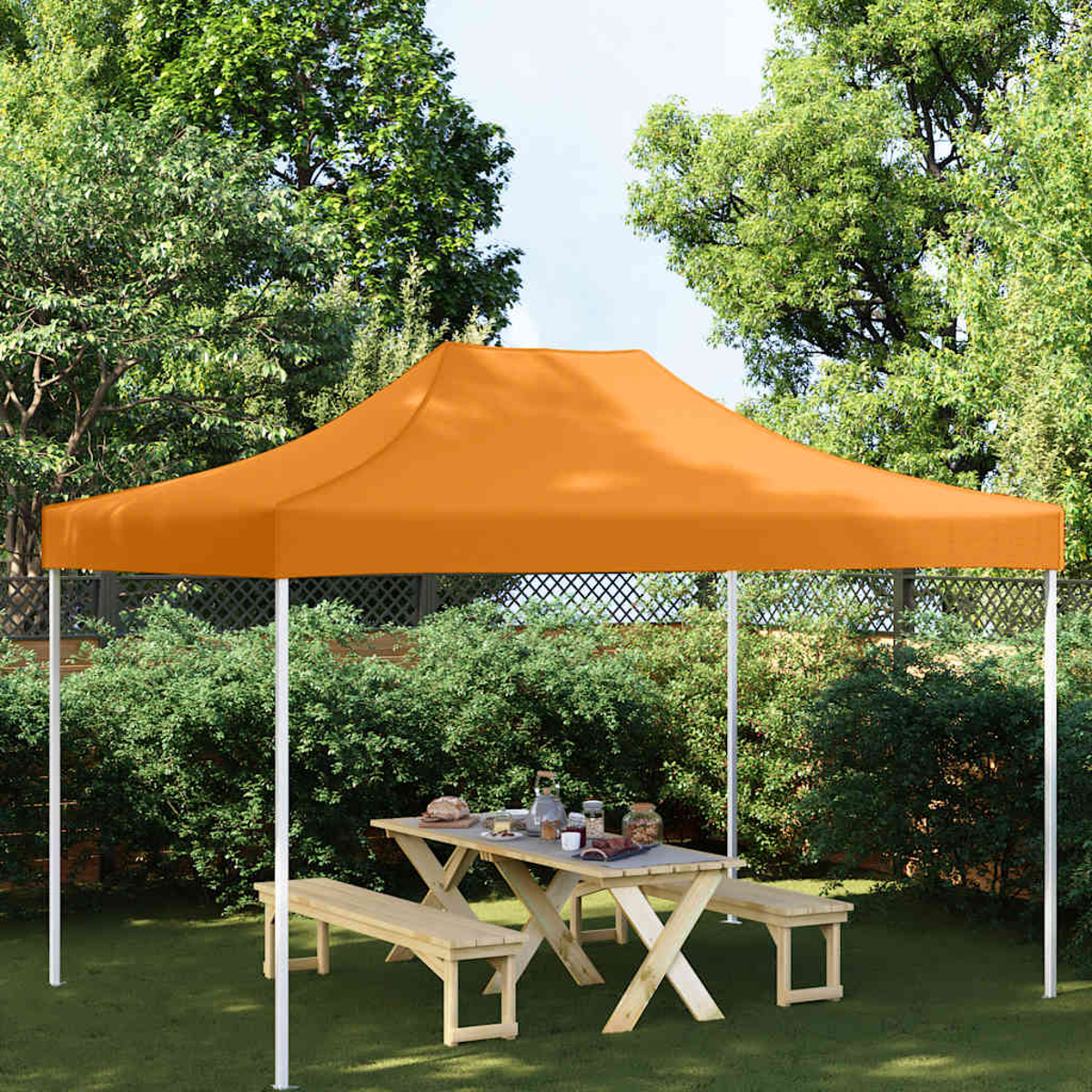Una tenda arancione copre un tavolo da picnic con panche in un giardino.