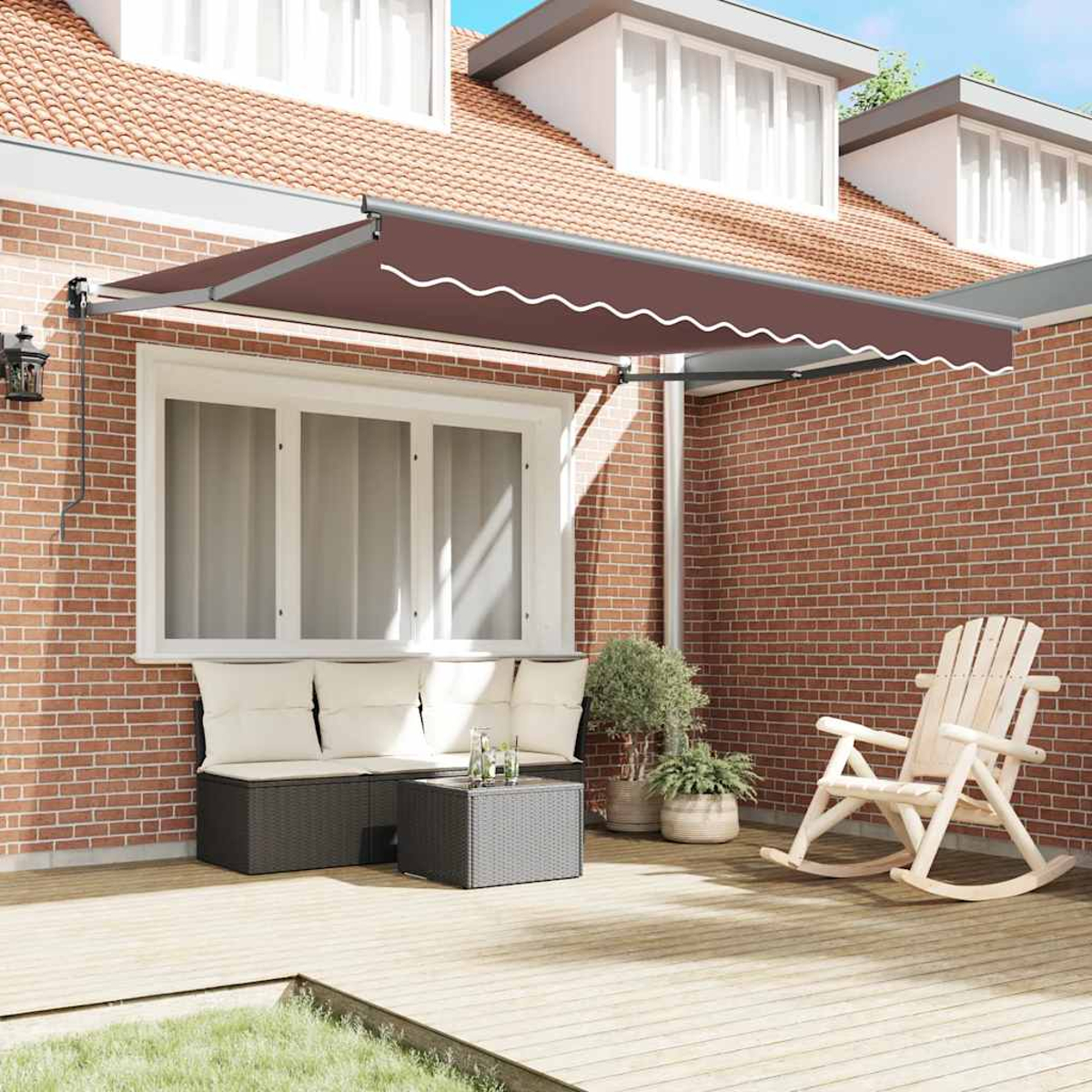 Una tenda da sole marrone sopra una finestra con divano in rattan, tavolino e dondolo.