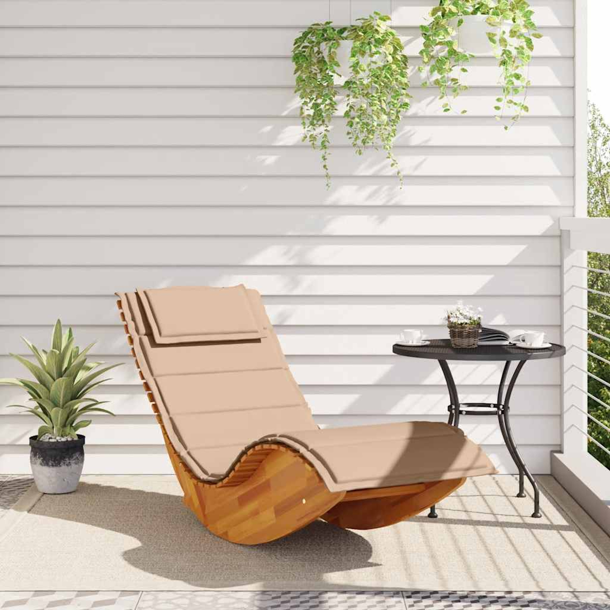 Una sdraio beige su un balcone accanto a un tavolino con tazze.