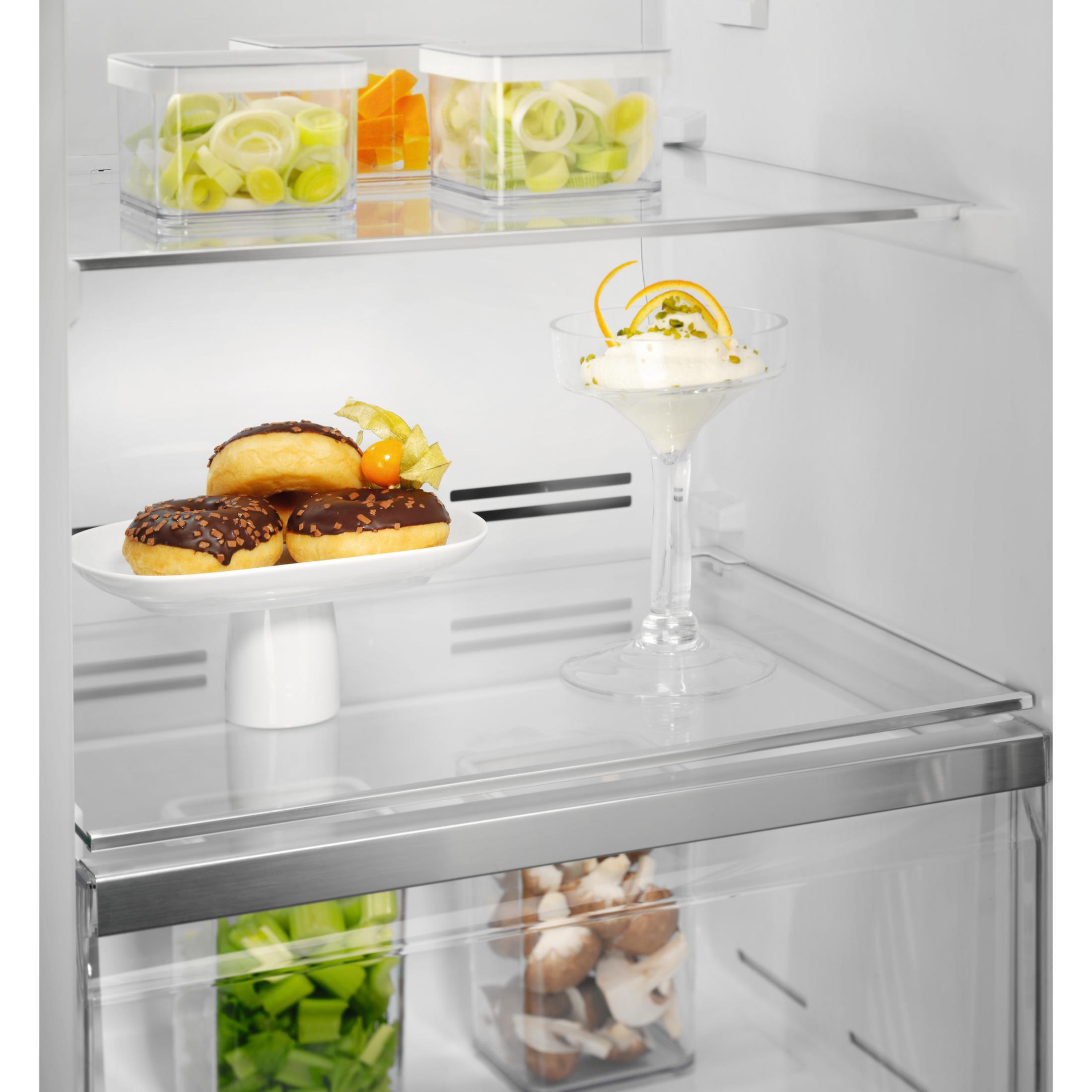 Intérieur de réfrigérateur avec nourriture : donuts, glace, poireaux et champignons en boîtes.