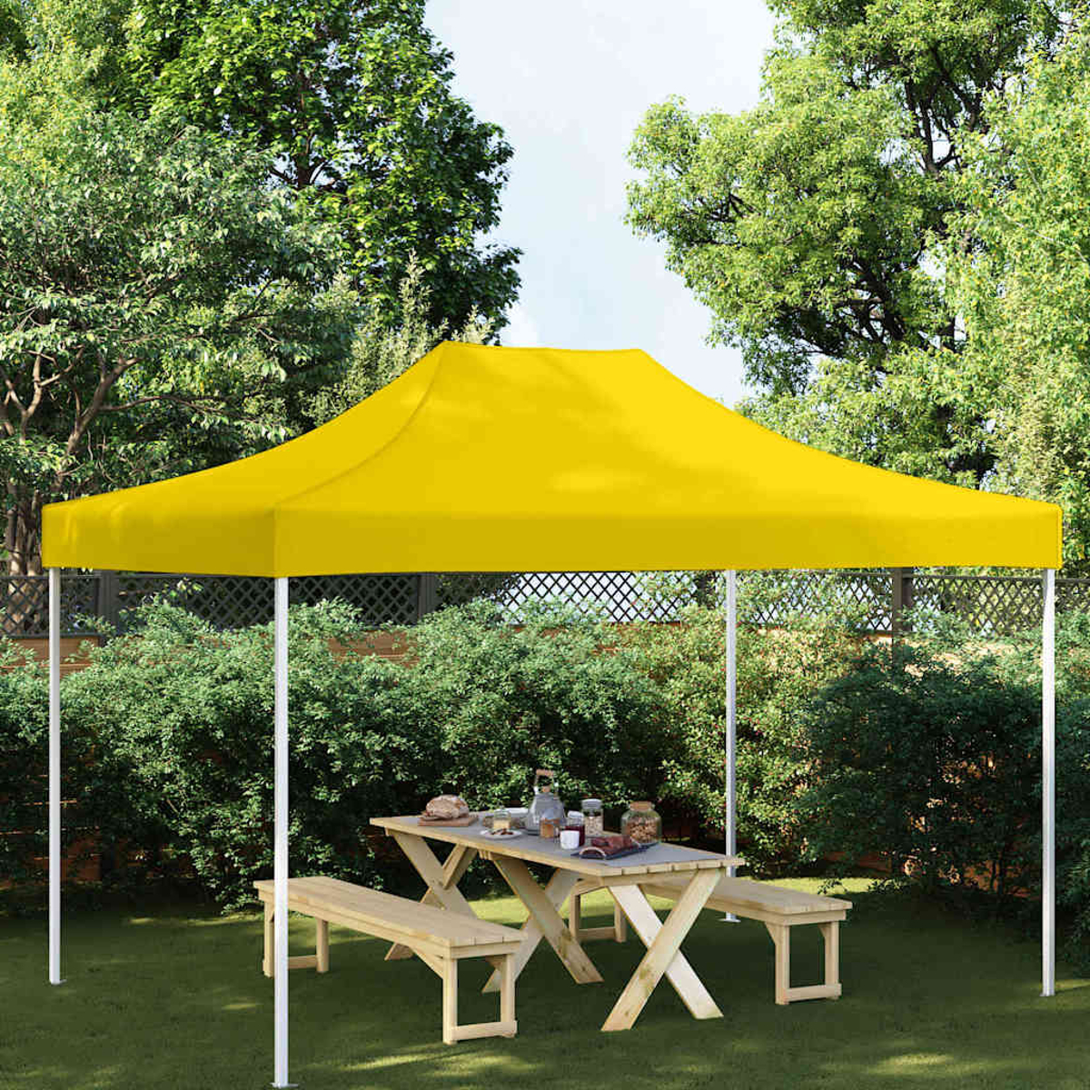 Una tenda gialla su un tavolo di legno con panche in un giardino.