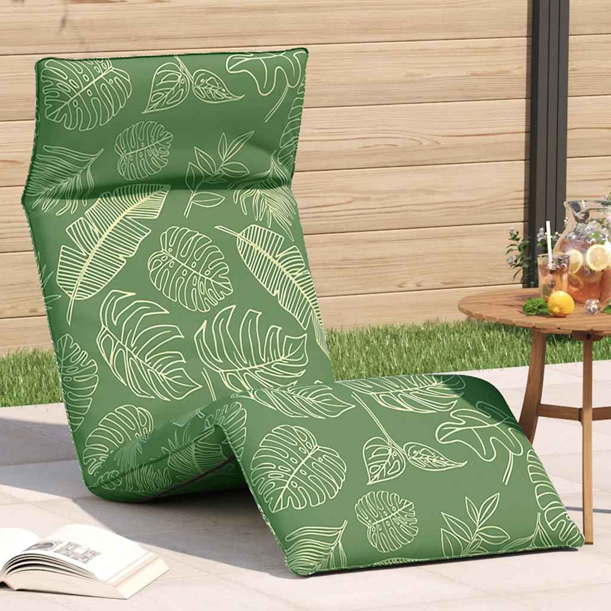 Cuscino verde per sdraio con motivo a foglie su un patio accanto a un tavolo con bevande.