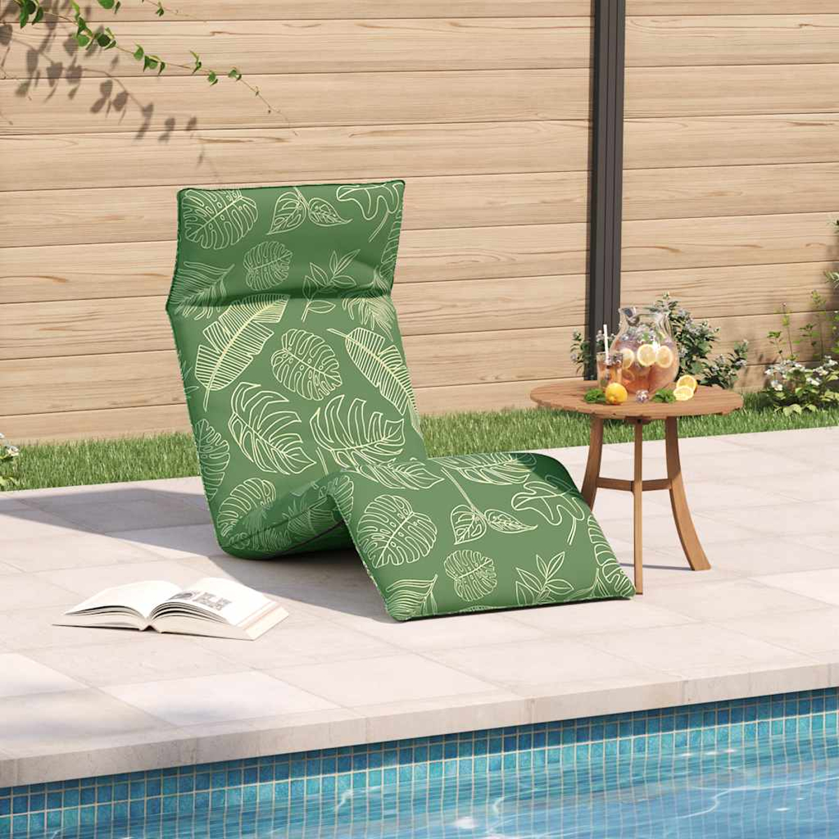 Sdraio verde con stampa a foglia vicino alla piscina con tavolo e bevande.
