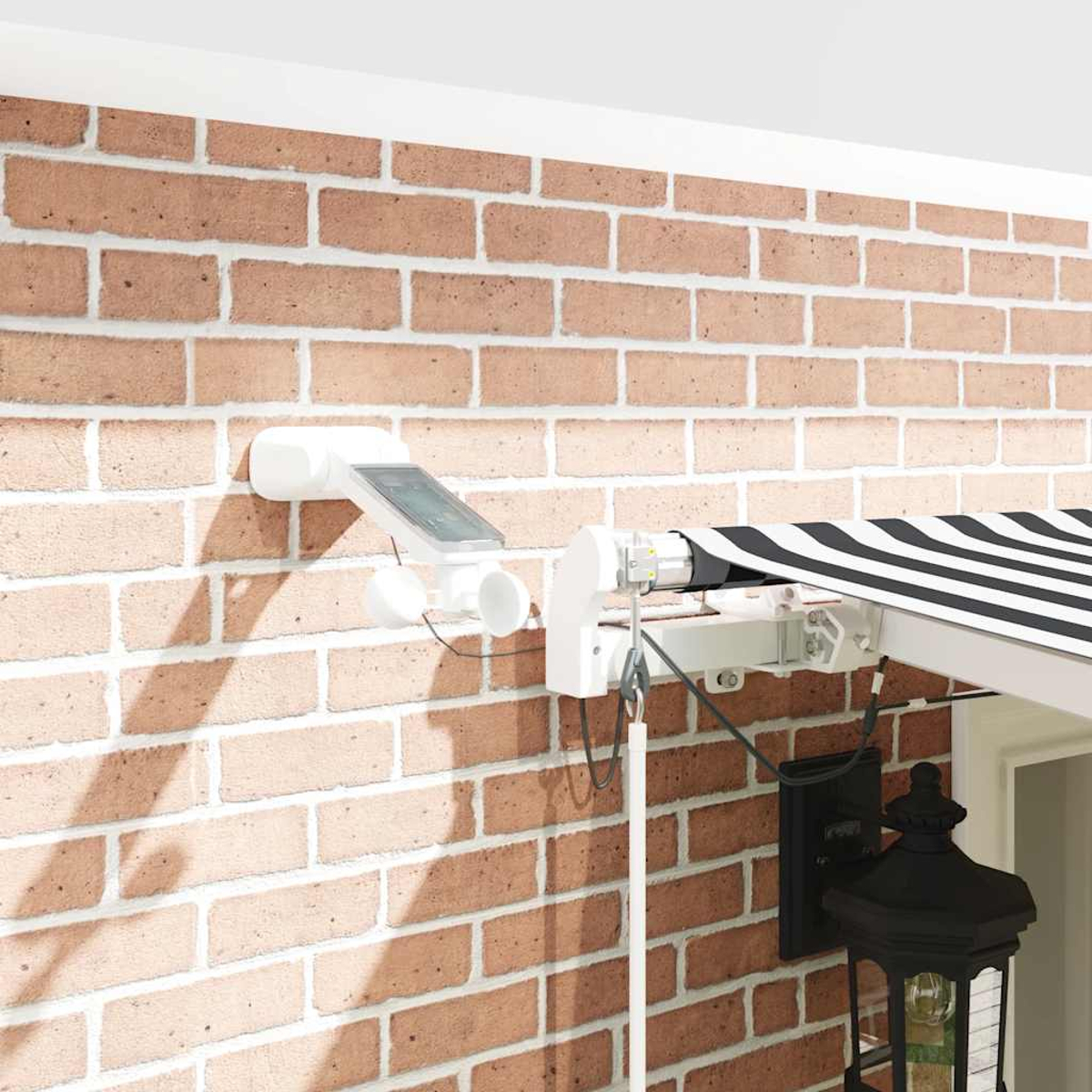 Un sistema di tenda da sole bianco con pannello solare e anemometro montato su un muro di mattoni.