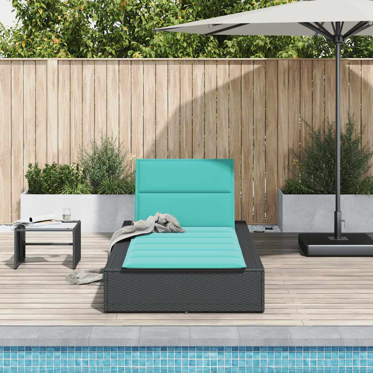 Una chaise longue turchese con cuscini si trova su un ponte di legno vicino a una piscina.