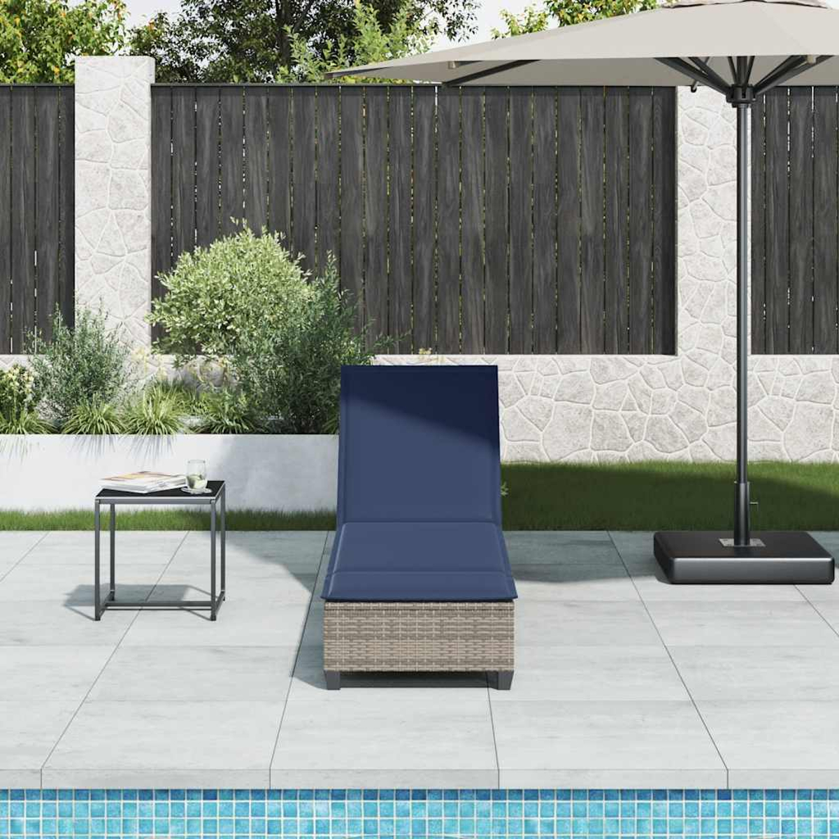 Una chaise longue con cuscino blu è vicino a una piscina, con tavolino e ombrellone.