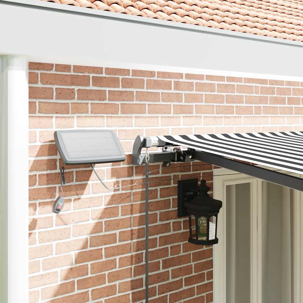 Tenda da sole a righe bianche e nere, pannello solare e lanterna su muro di mattoni.