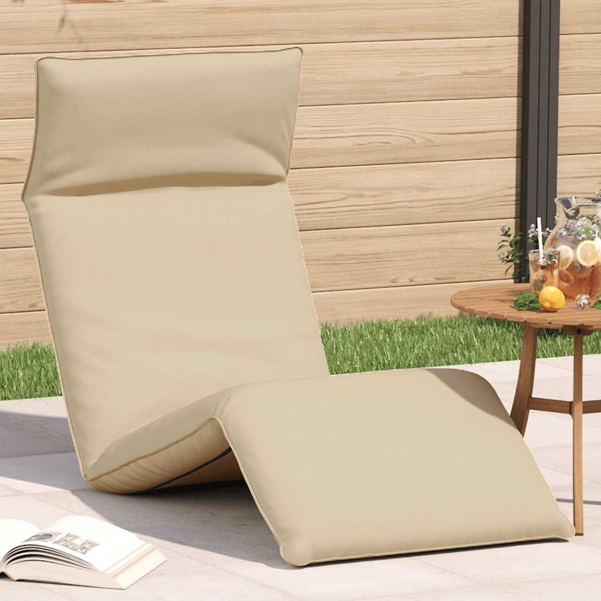 Una sedia a sdraio color crema si trova su un patio con recinzione in legno e erba sullo sfondo.