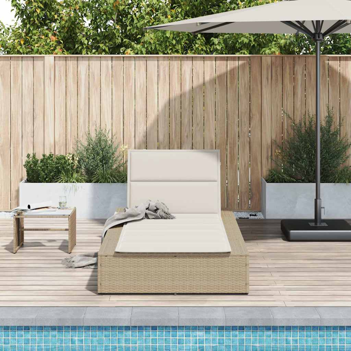 Una chaise longue in rattan beige con cuscini e coperta su un ponte di legno vicino a una piscina.