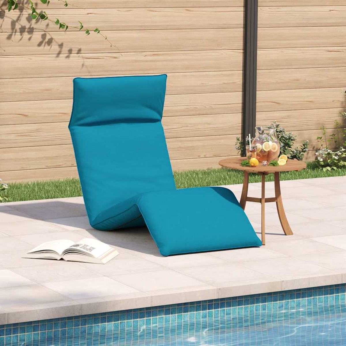 Una chaise longue blu vicino a una piscina con un libro e un drink su un tavolino.