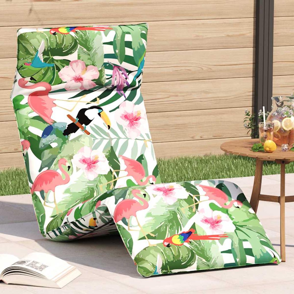 Una sdraio e un cuscino con fantasia tropicale di fenicotteri, uccelli e fiori.