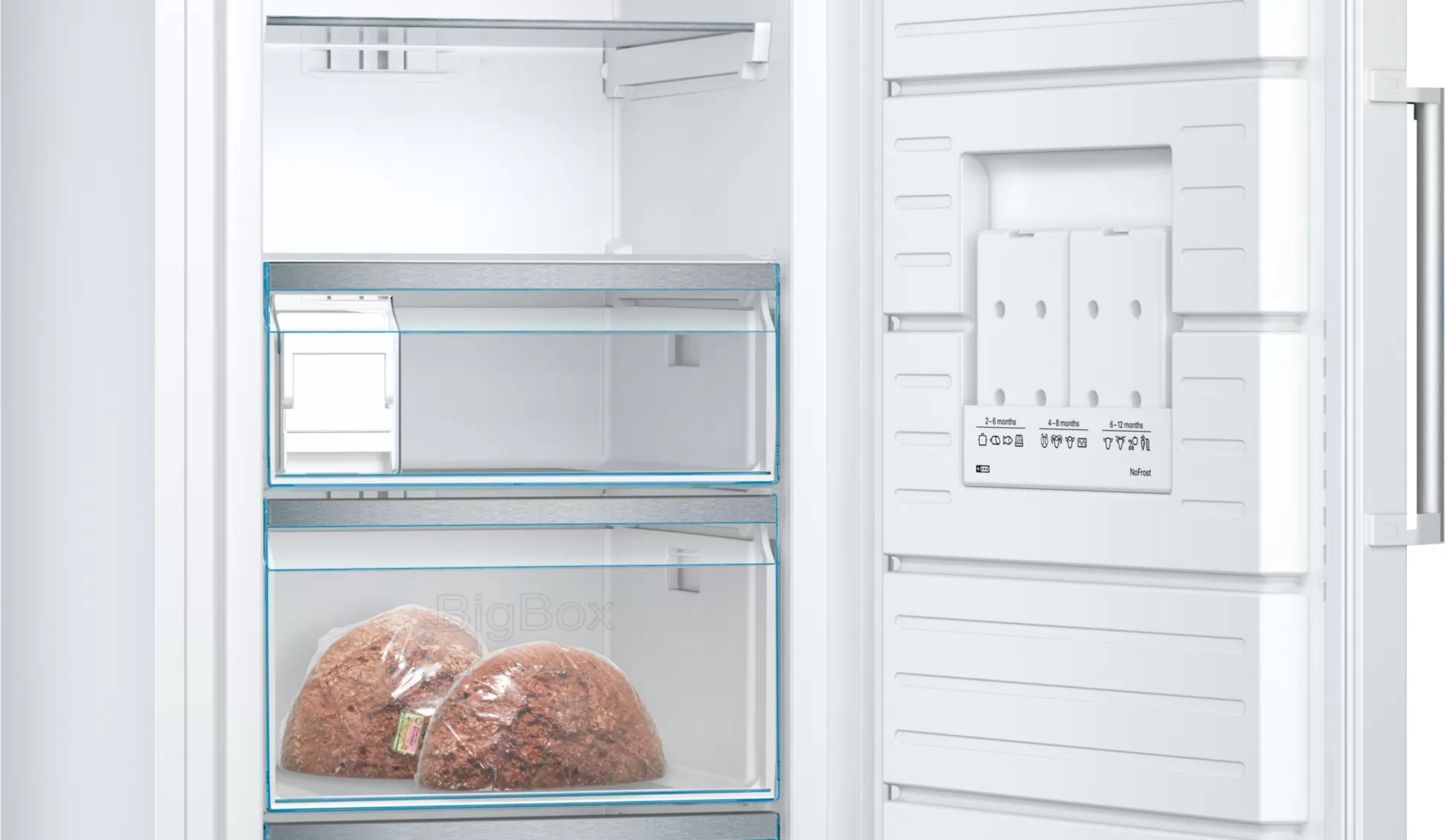 Un congelatore bianco aperto con due sacchi di carne nel cassetto inferiore.