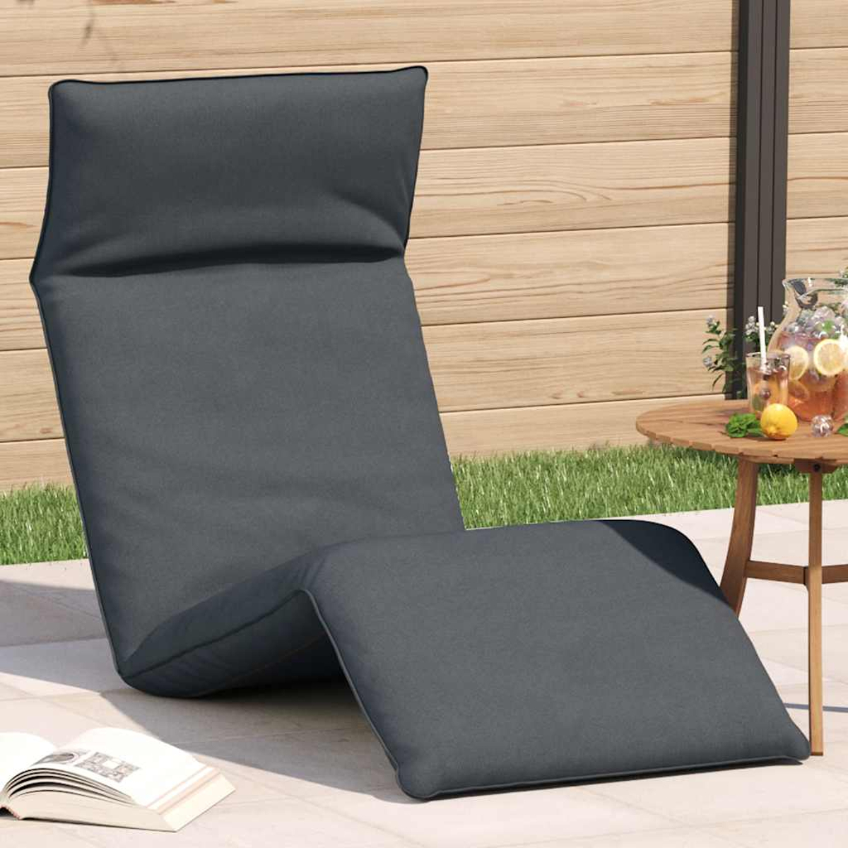 Ein dunkler Loungesessel steht auf einer Terrasse neben einem Holztisch mit Getränken.