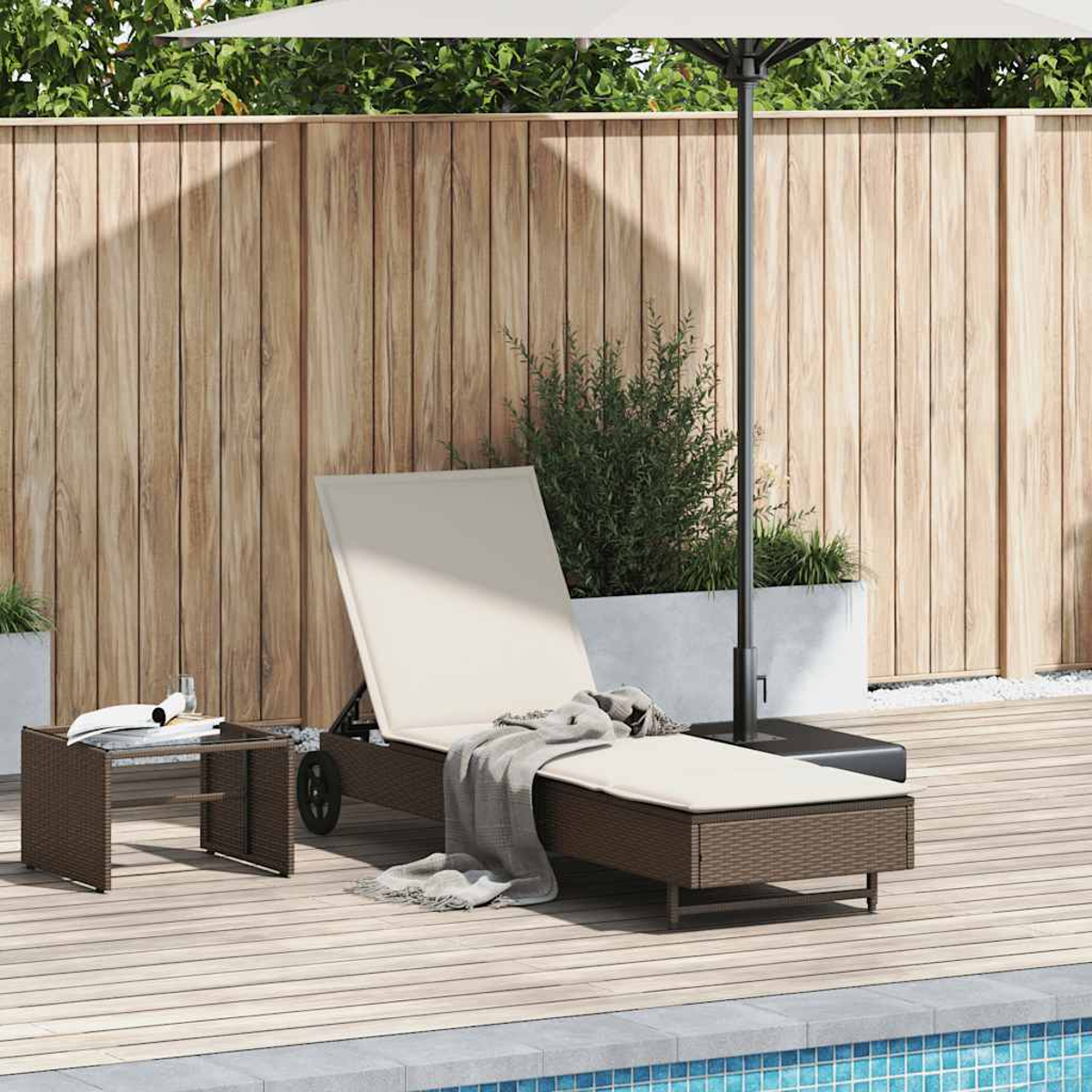 Un lettino prendisole in rattan marrone con cuscino beige e plaid grigio su un ponte di legno.