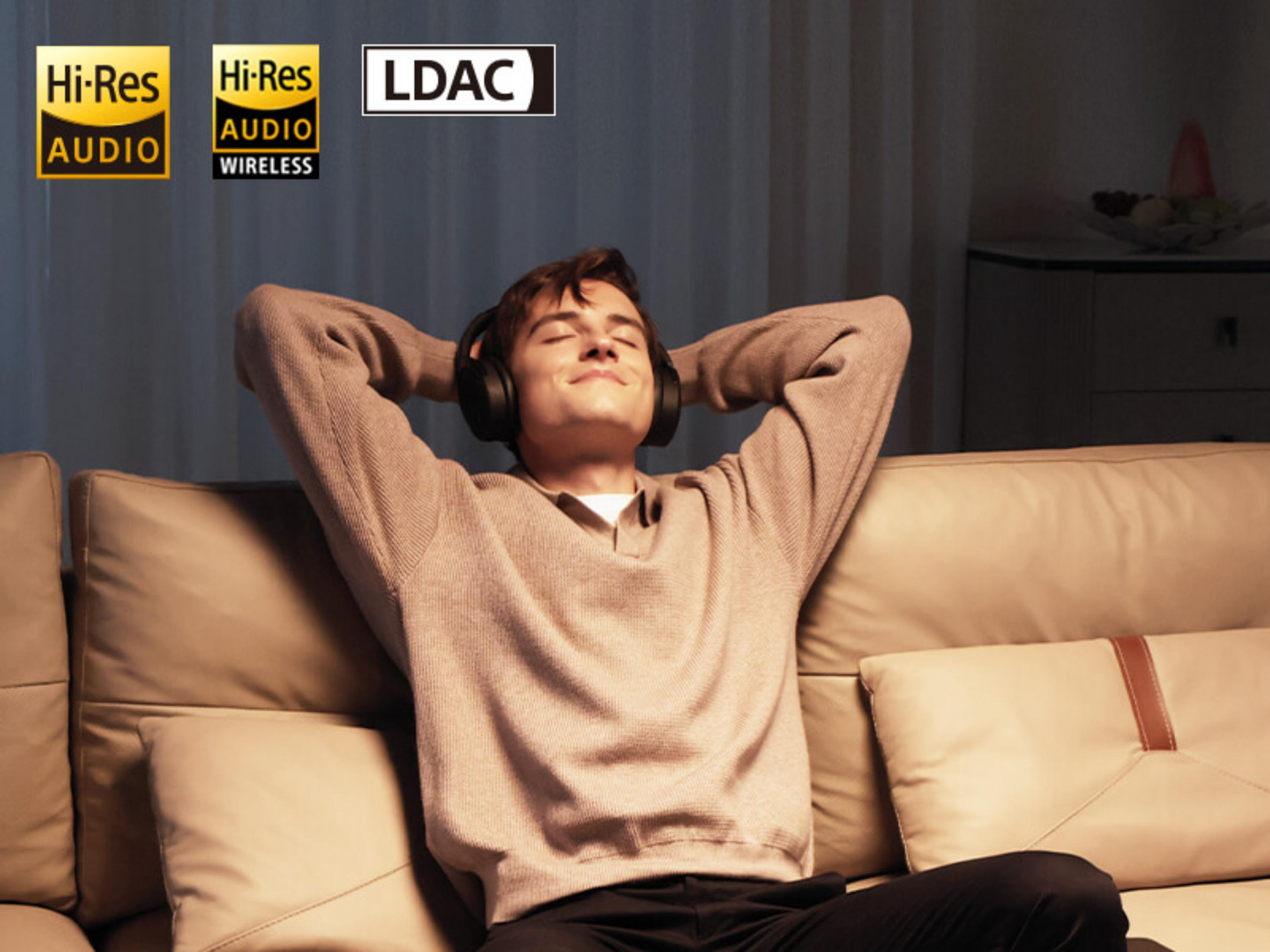 Mann mit Kopfhörern auf einem Sofa, mit Hi-Res Audio-Logos.