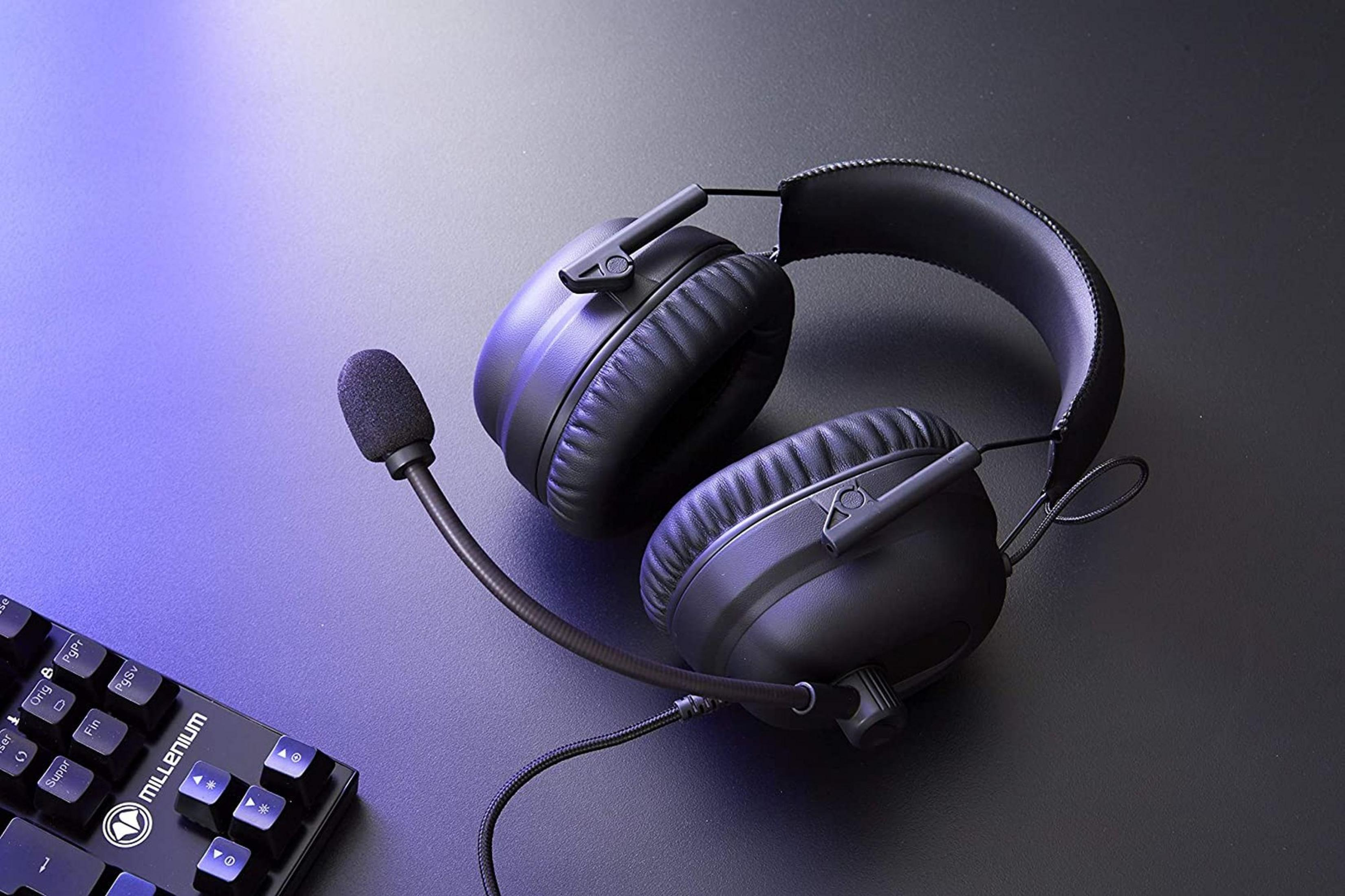 Auriculares negros para juegos con micrófono y teclado sobre fondo oscuro.