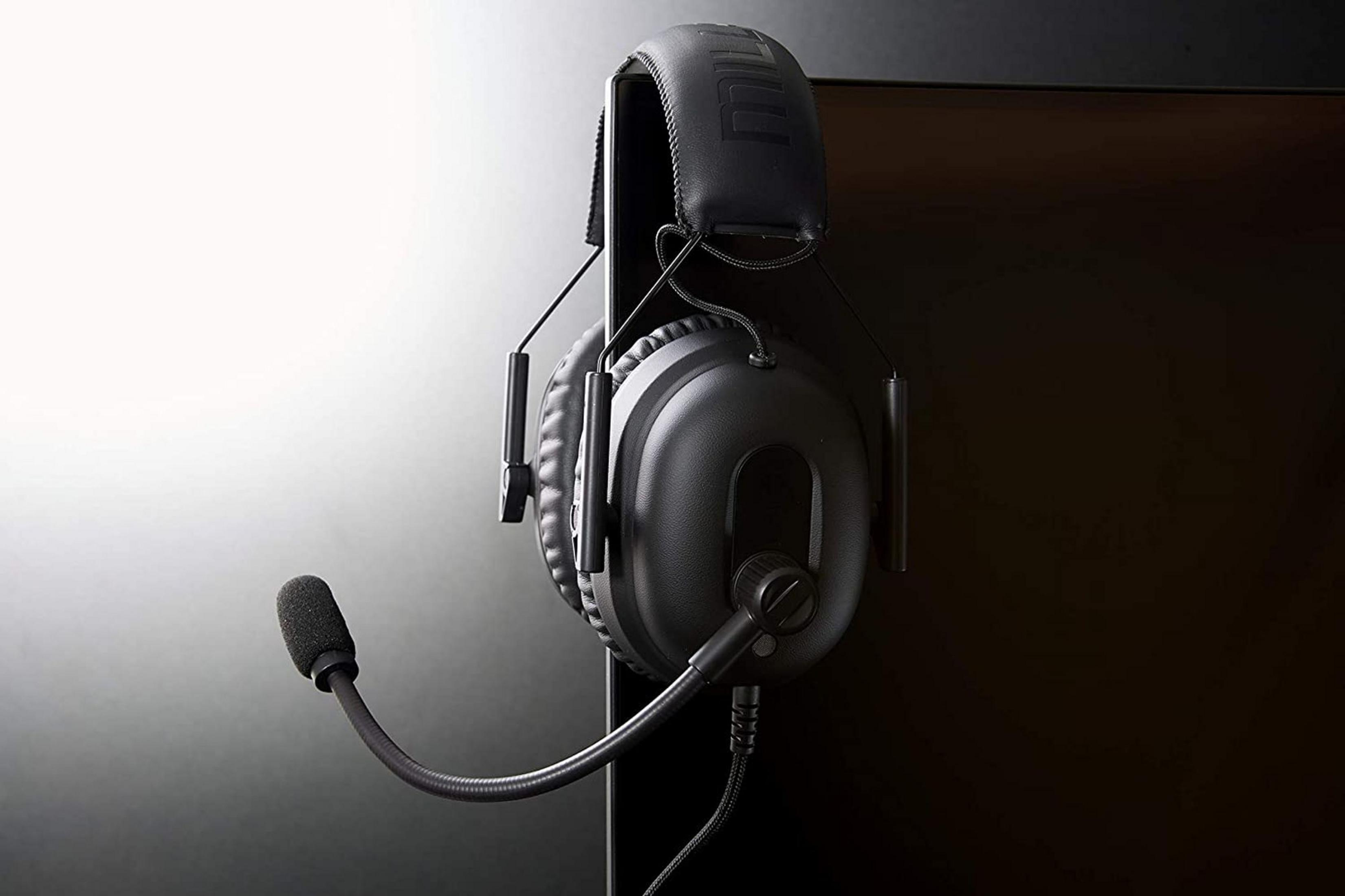 Auriculares negros con micrófono colgados en una pantalla oscura.