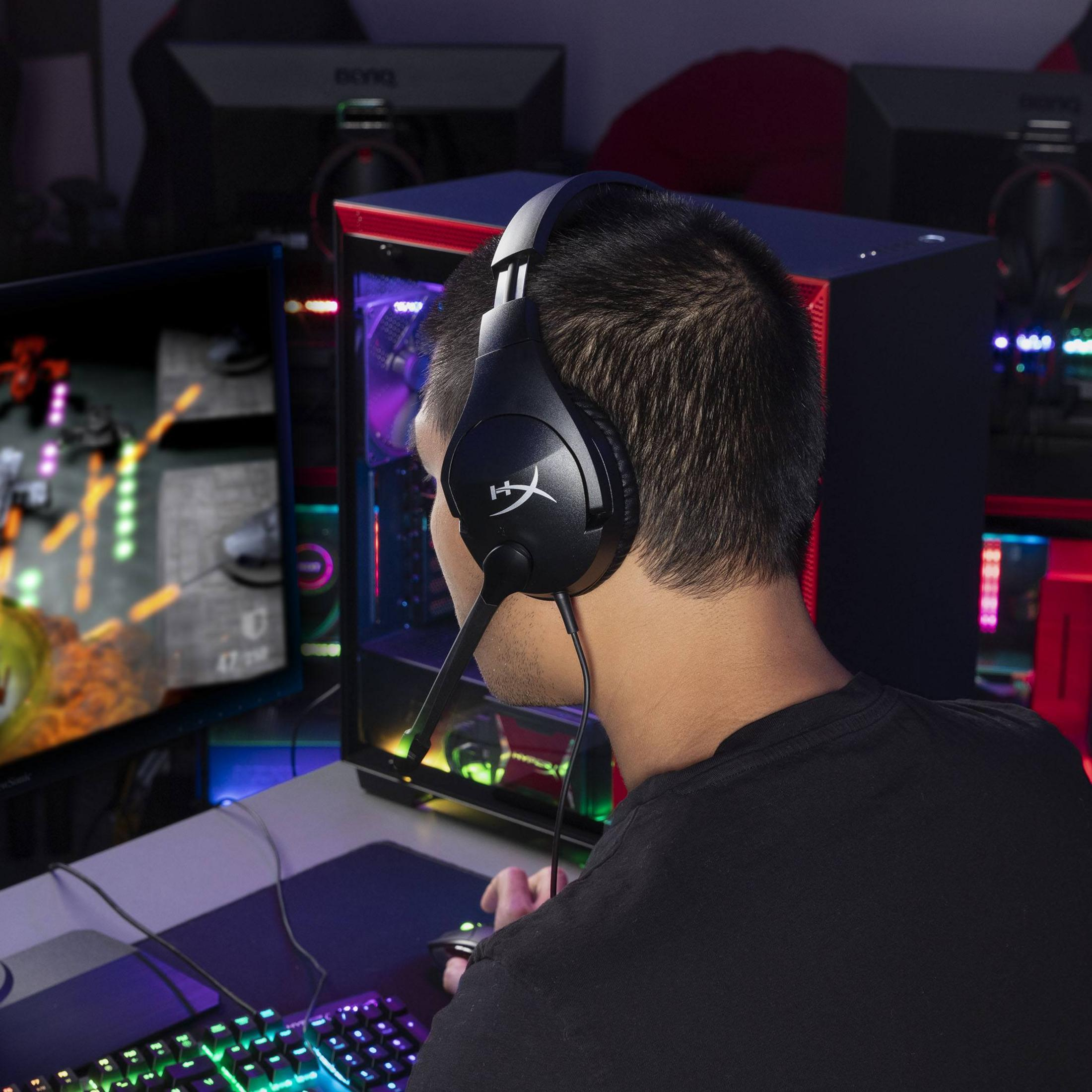 Un hombre con auriculares juega videojuegos frente a un PC con iluminación RGB.