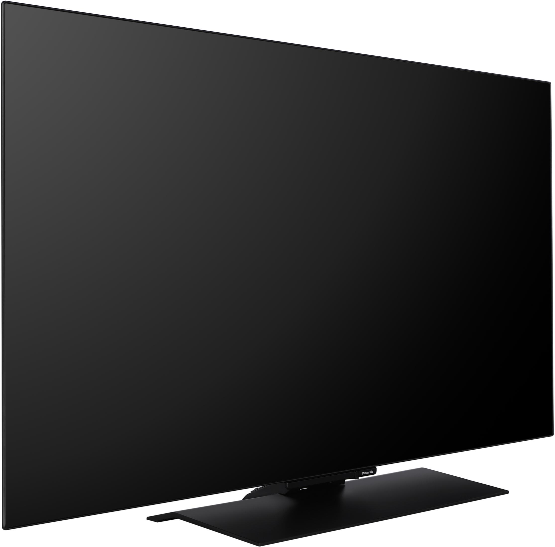 Un televisor negro con un soporte elegante, visto desde un ángulo.