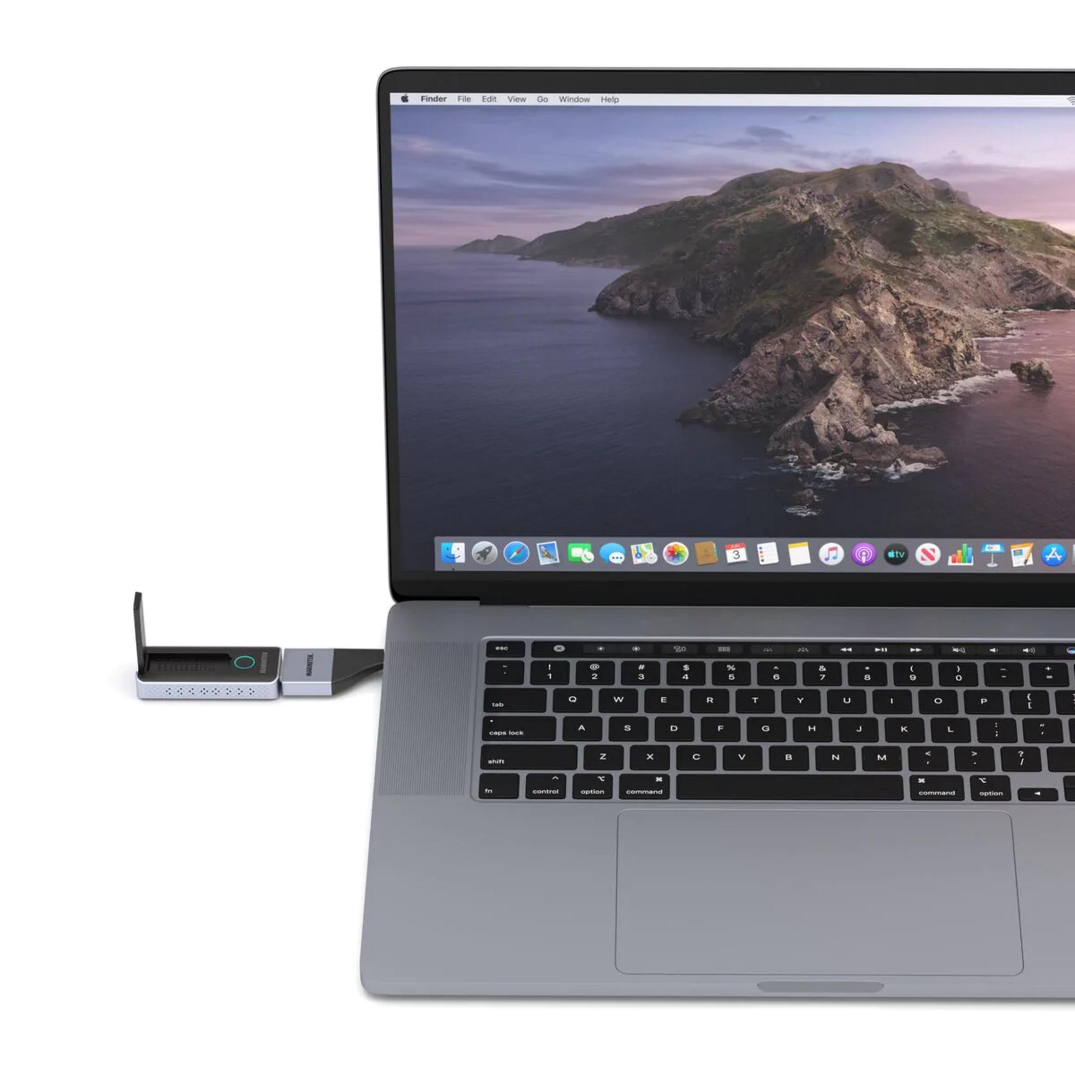 Un portátil con un hub USB-C conectado, con un fondo de pantalla de montaña y lago.