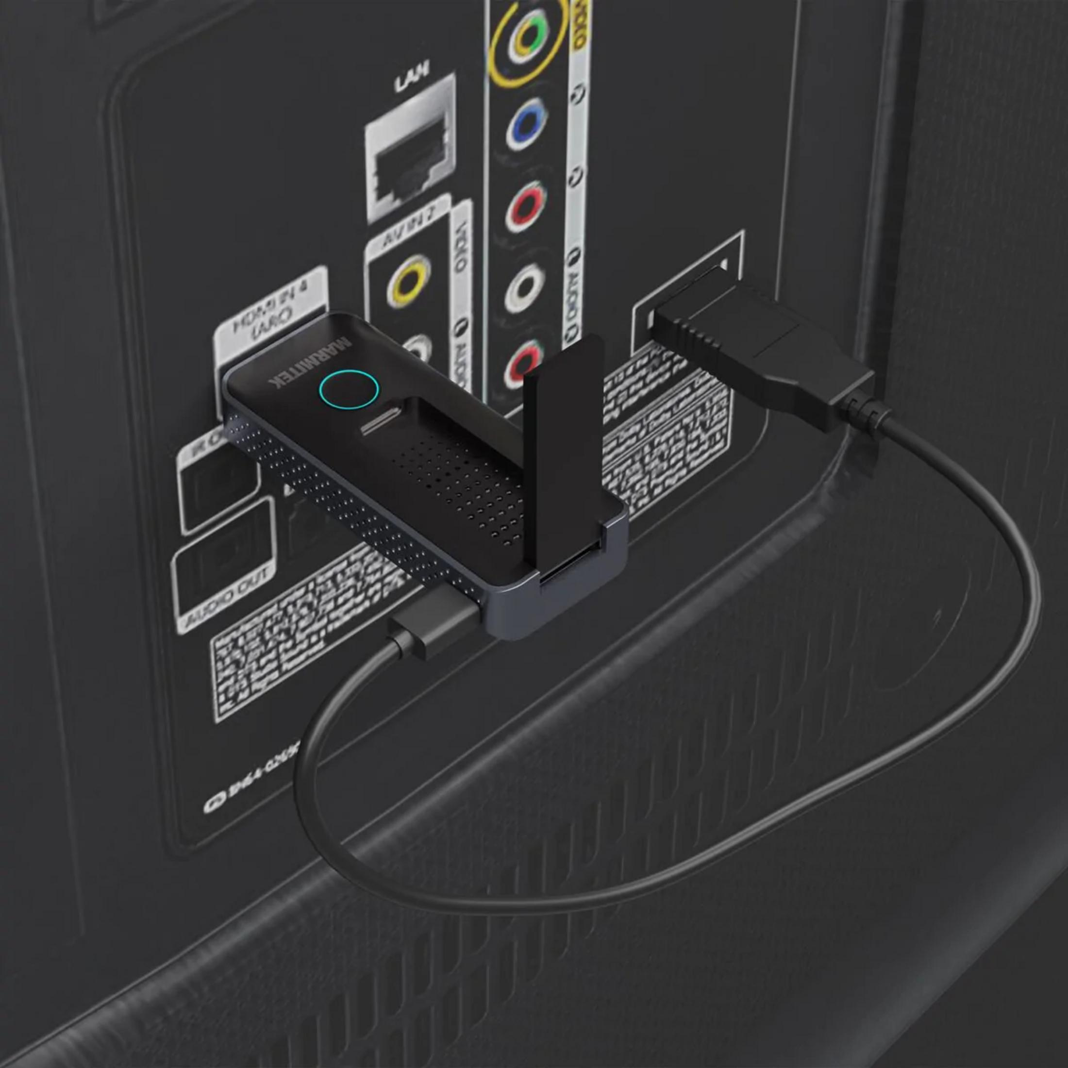 Un adaptador negro está conectado a los puertos de la parte trasera de un televisor.