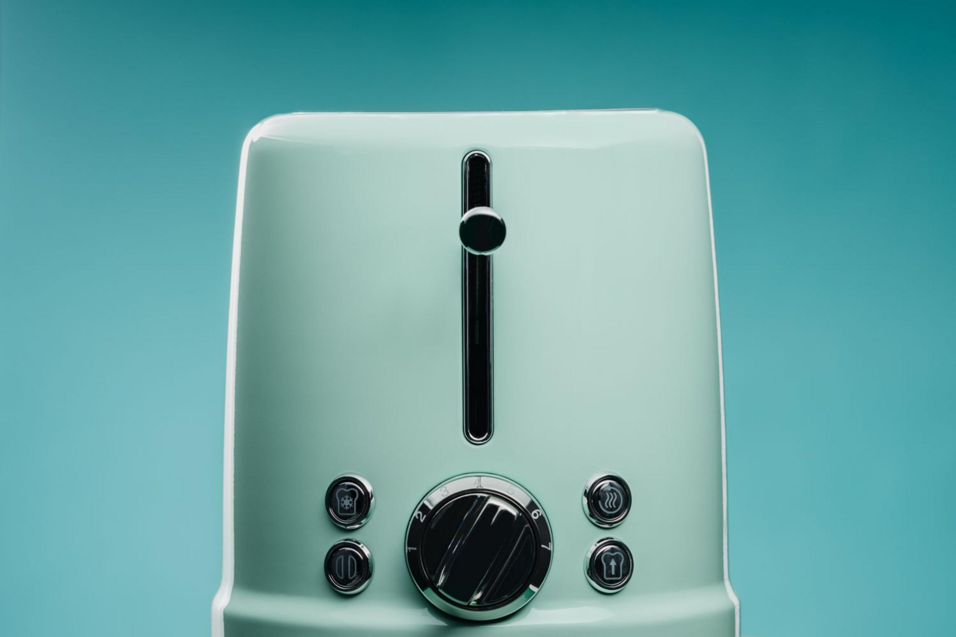 Un tostapane verde chiaro con dettagli cromati su sfondo blu.