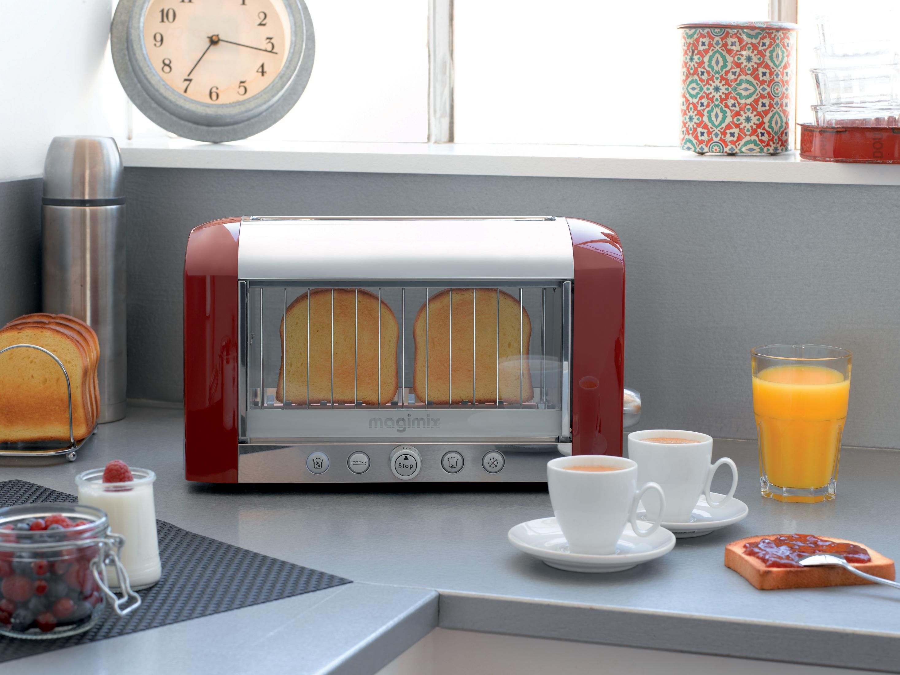 Tostapane rosso con toast, caffè, succo e bacche su un bancone da cucina.
