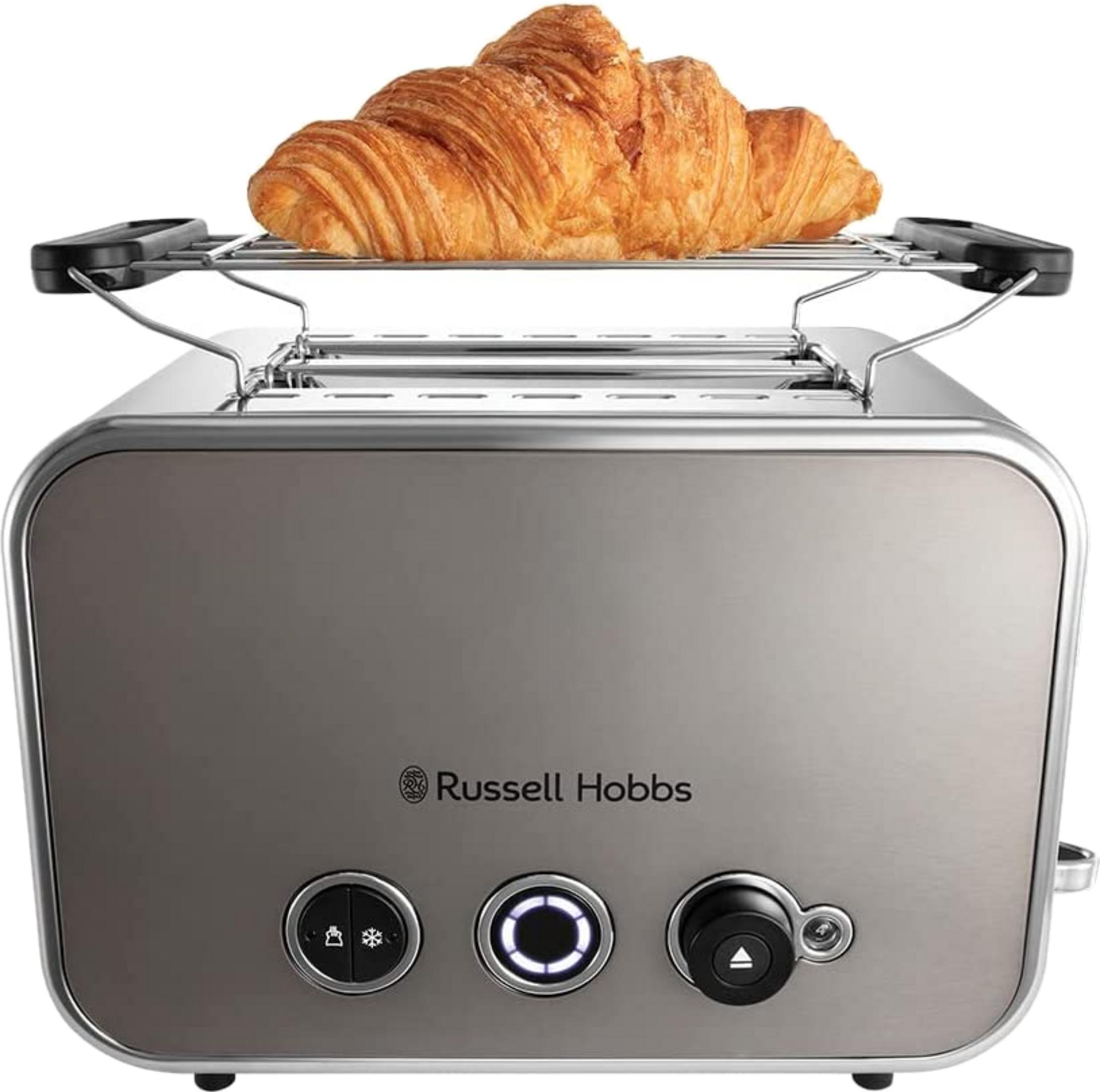 Ein Croissant liegt auf einem Toaster aus gebürstetem Metall.