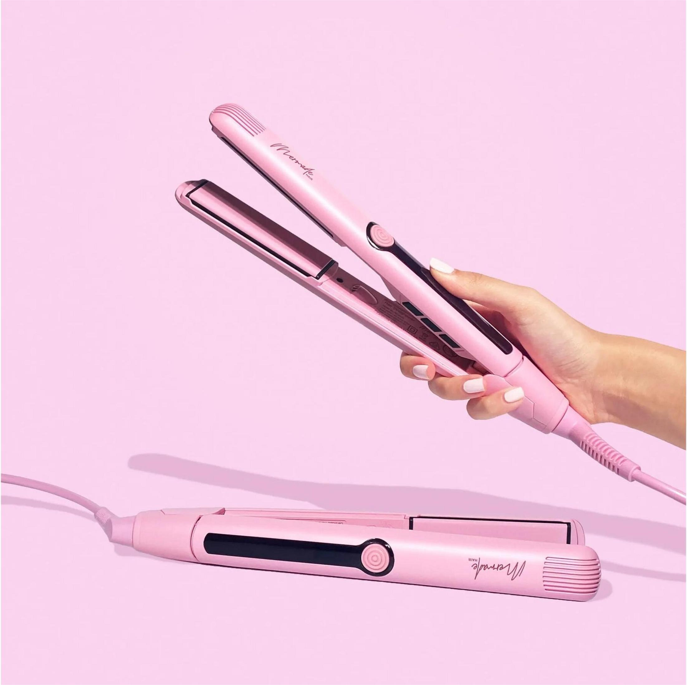 Eine Person hält einen rosa Haarglätter vor einem rosa Hintergrund.